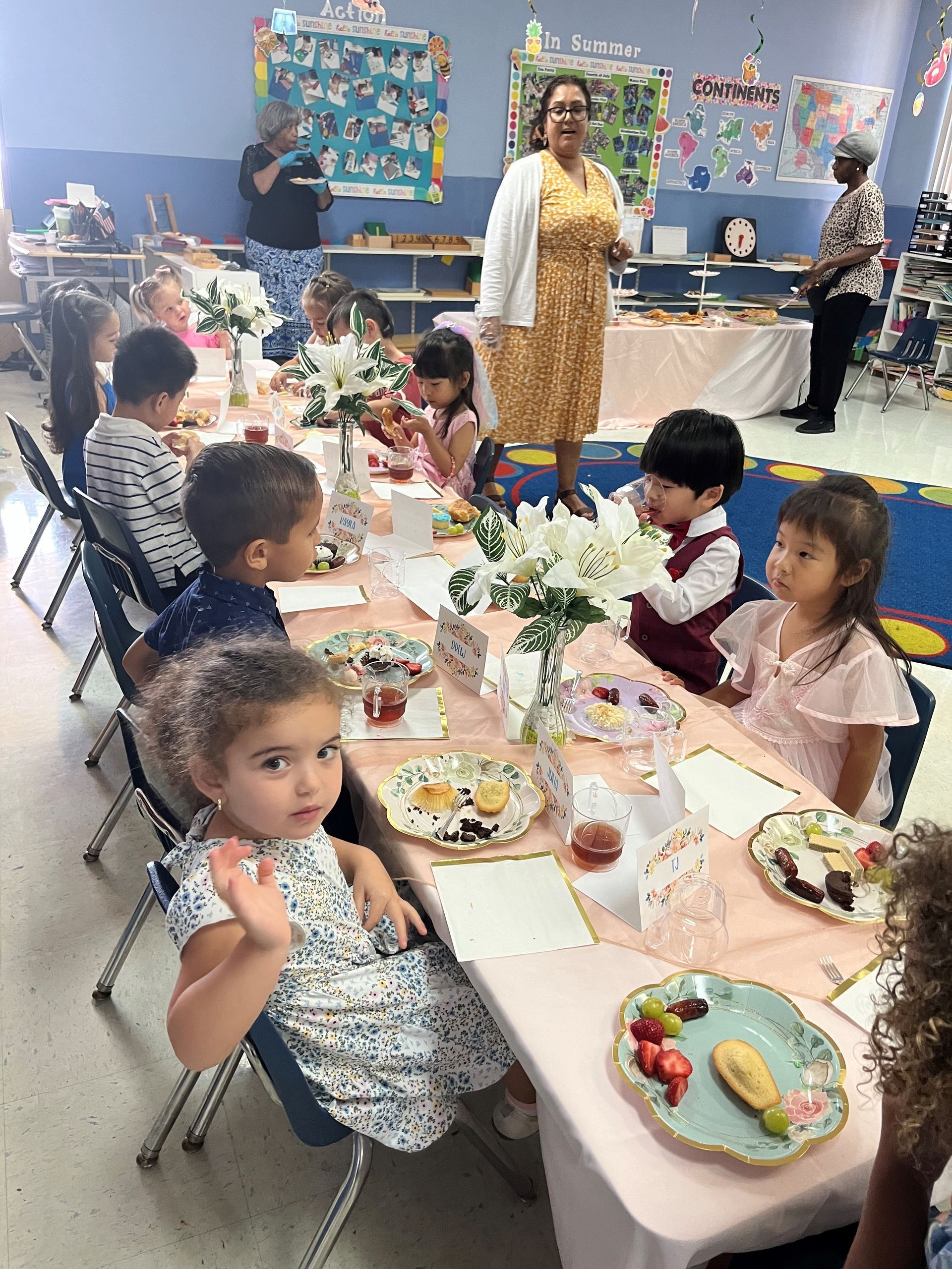 A group of children are sitting at tables with plates of food.