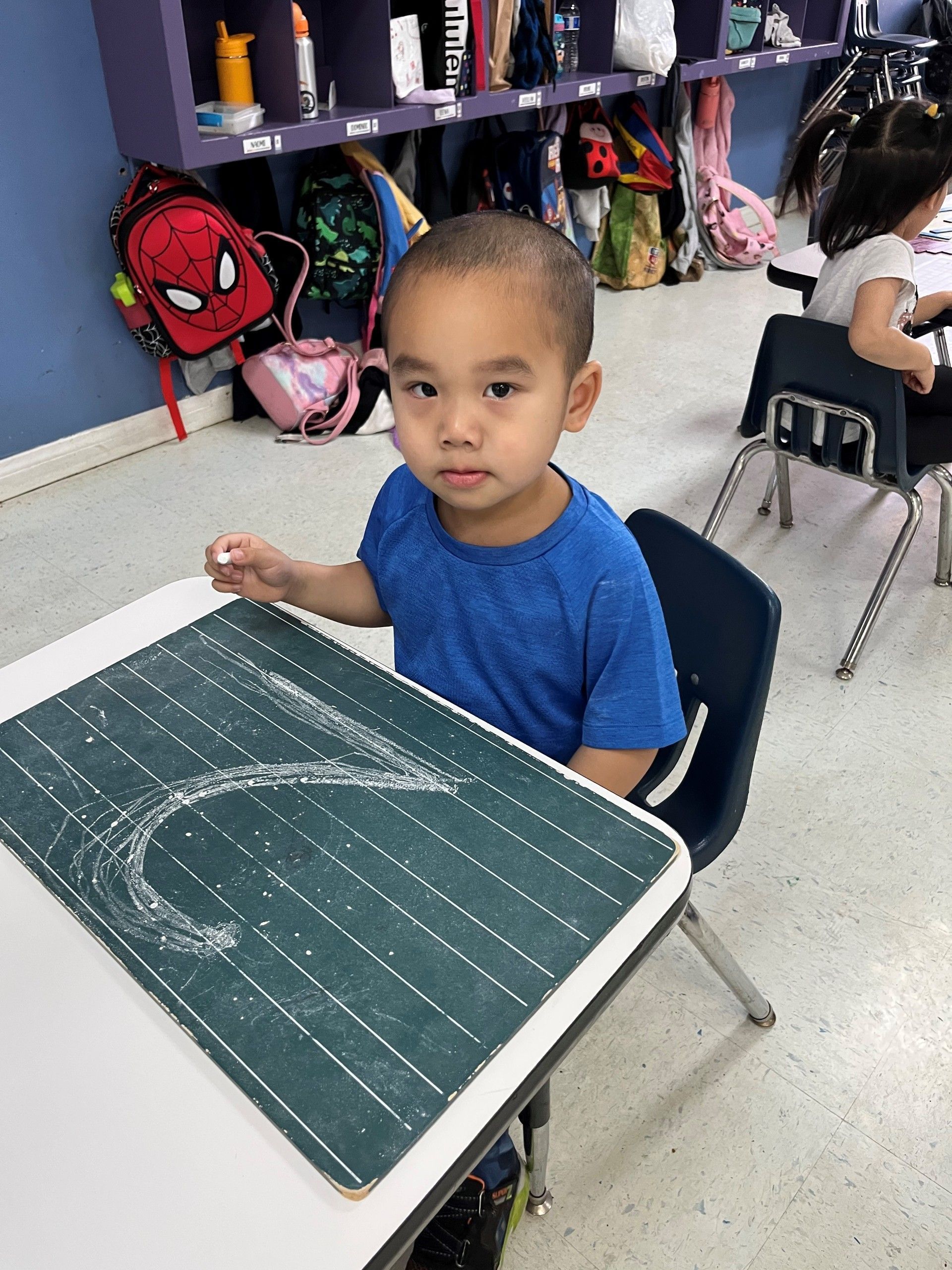 A young boy is sitting at a desk in a classroom