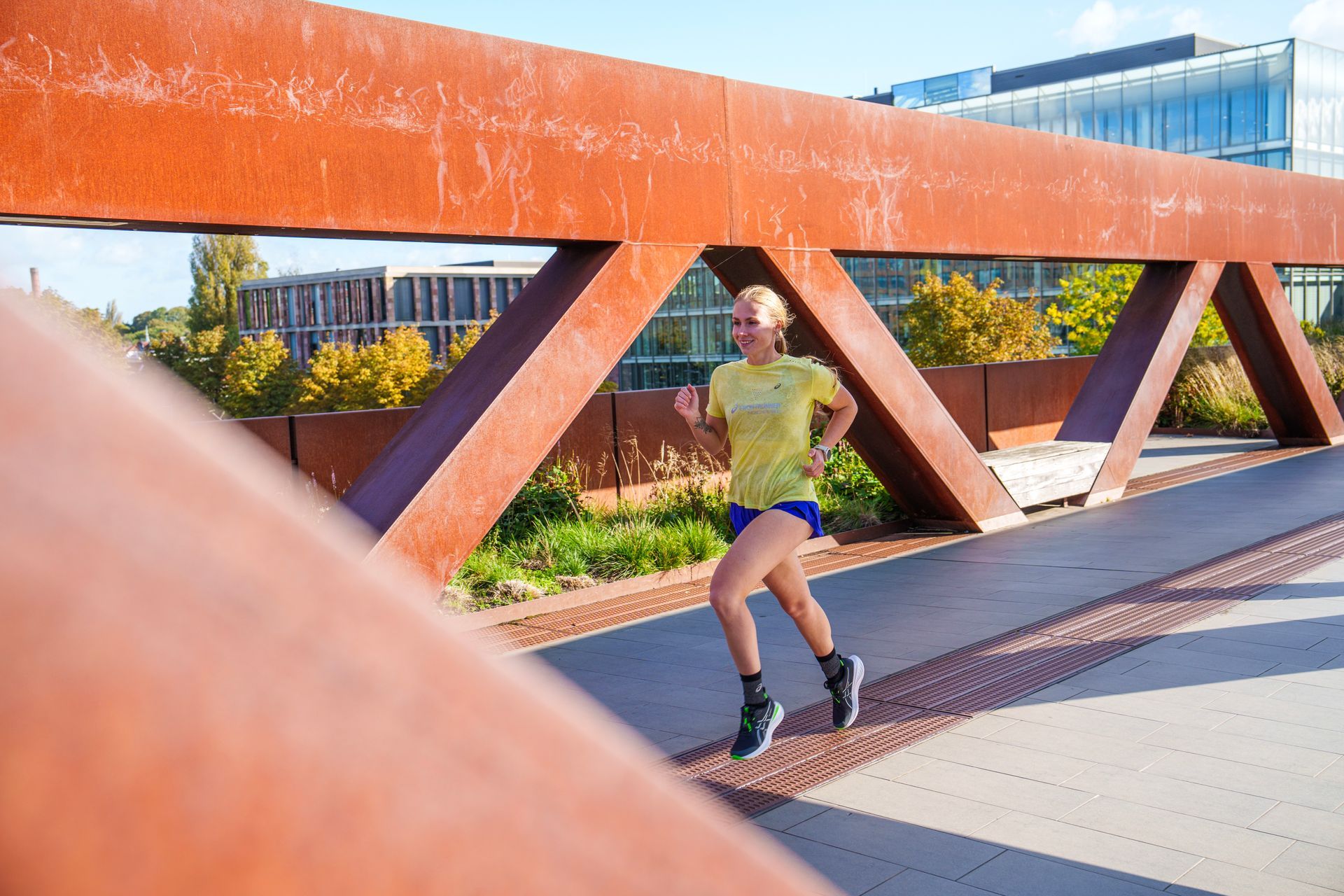 Een vrouw rent over een brug in een park.