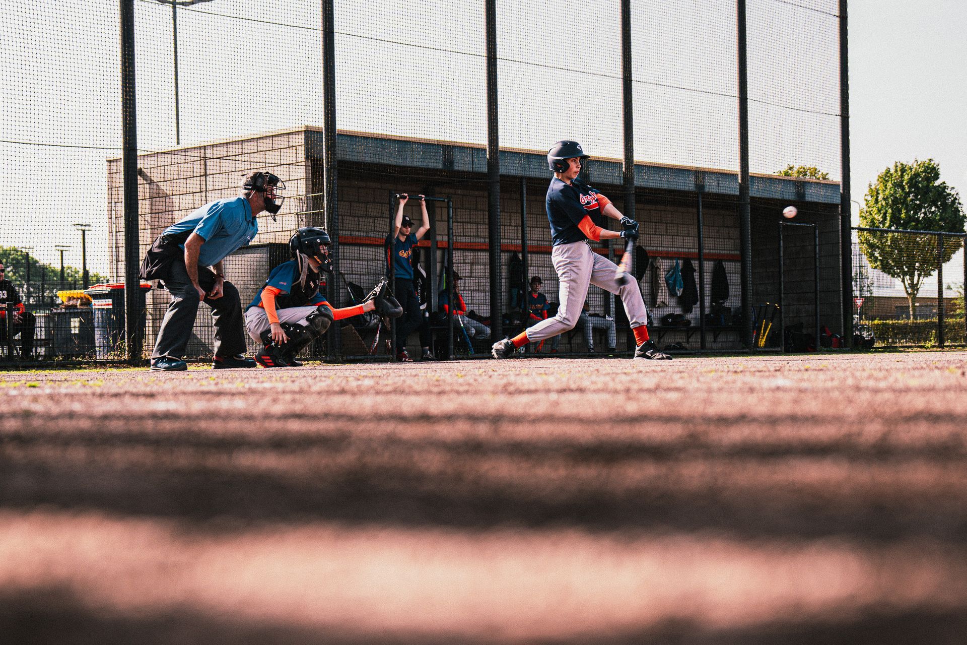 Een honkbalspeler slaat de bal naar de worp terwijl een catcher toekijkt.