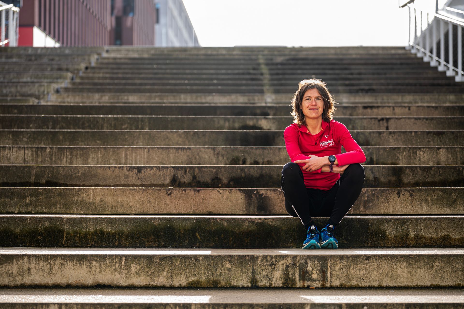 Een vrouw zit op een trap met haar benen gekruist.