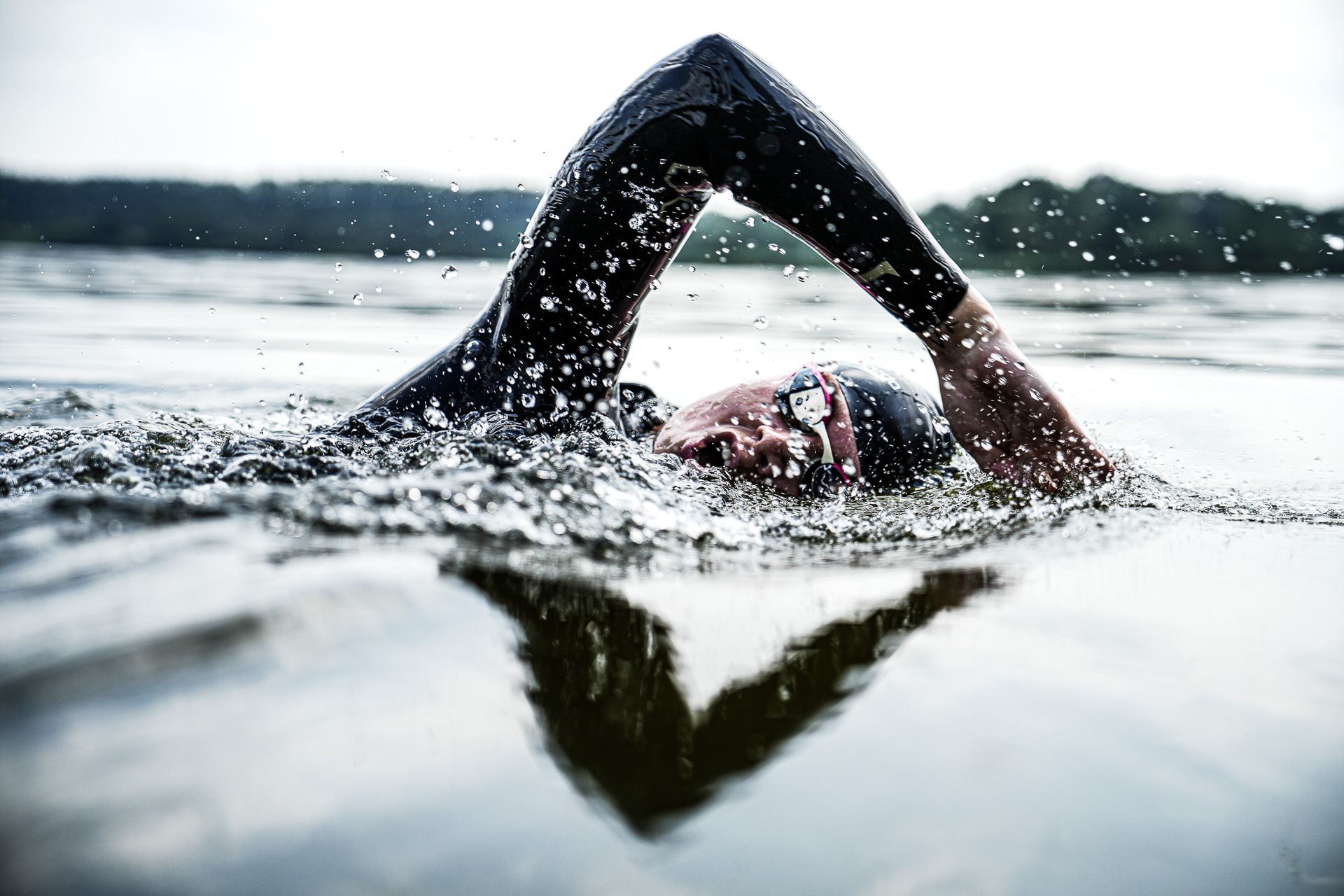 Een man in een wetsuit zwemt in een meer.