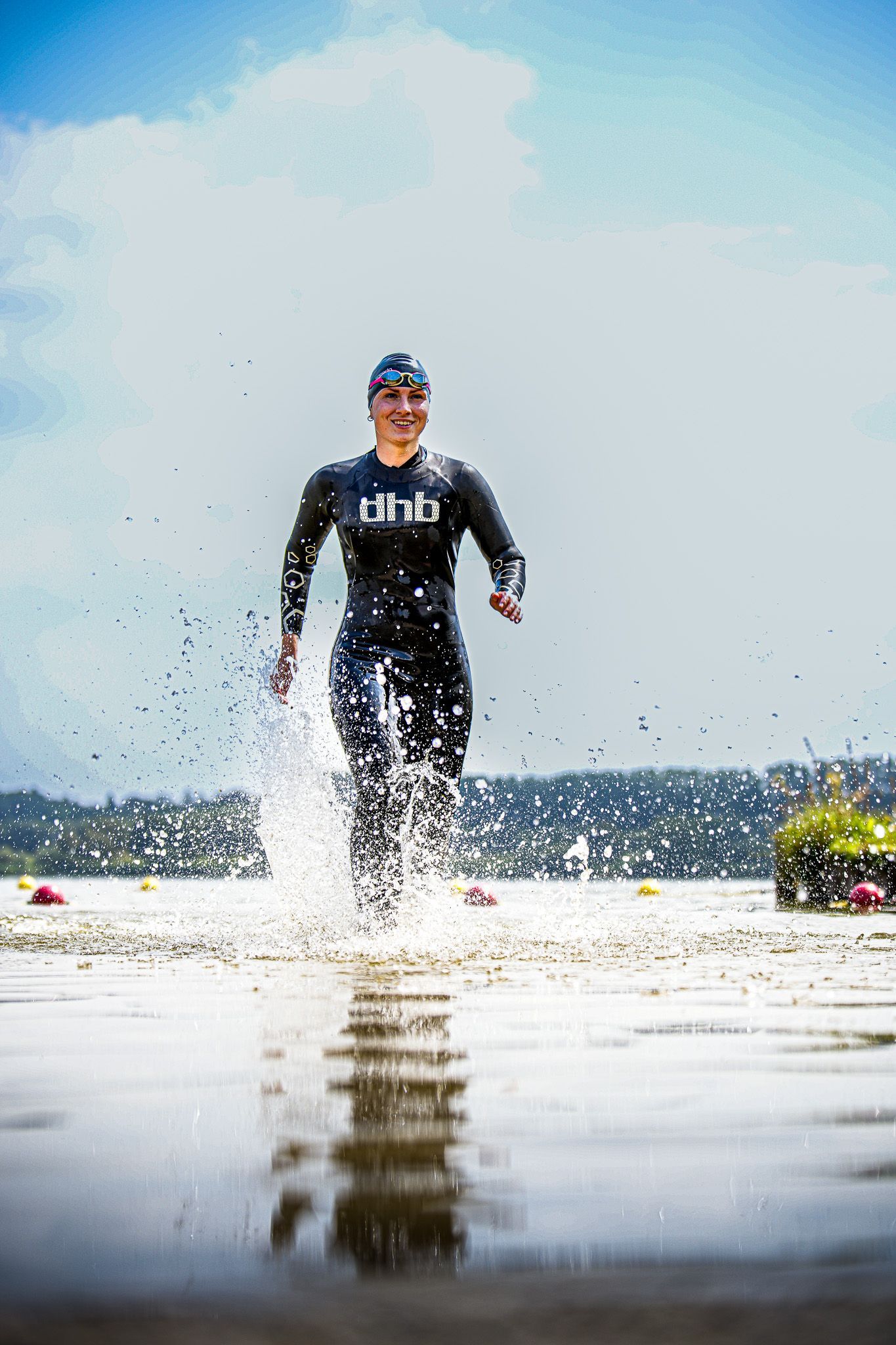 Een man in een wetsuit rent door het water op een strand.