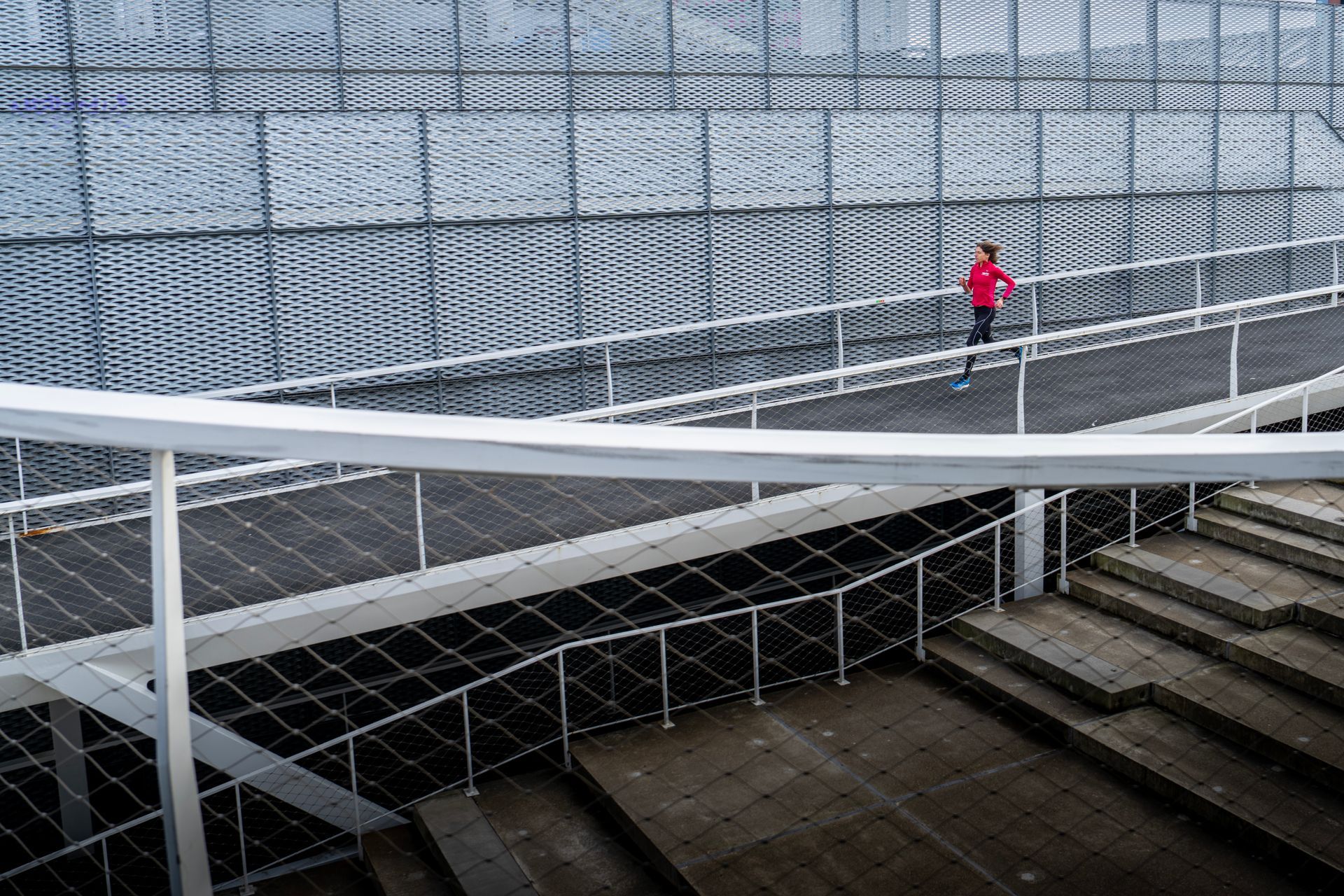 Een man in een rood shirt loopt over een brug met trappen.