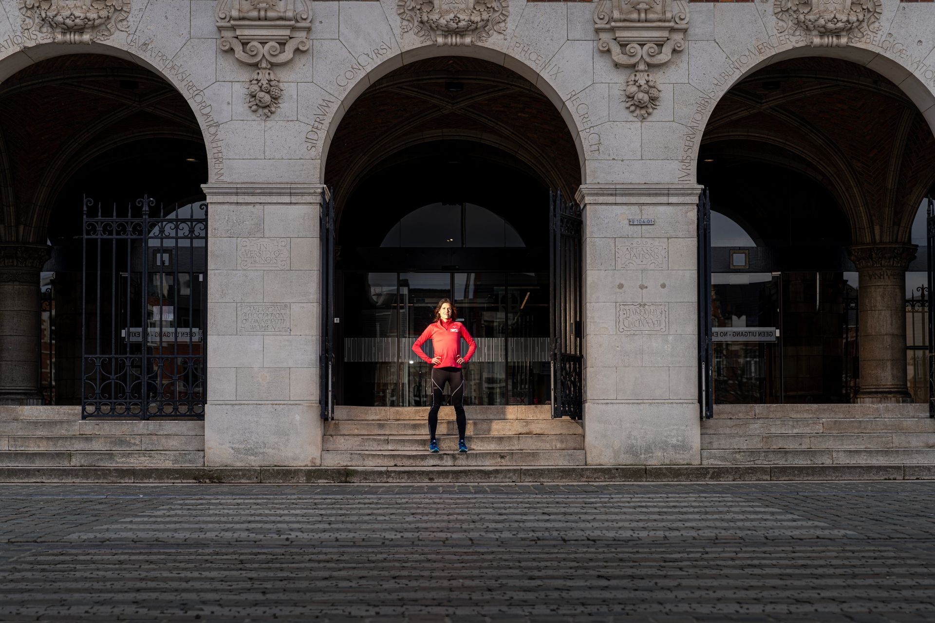 Een man in een rood jasje staat op de trappen van een gebouw.