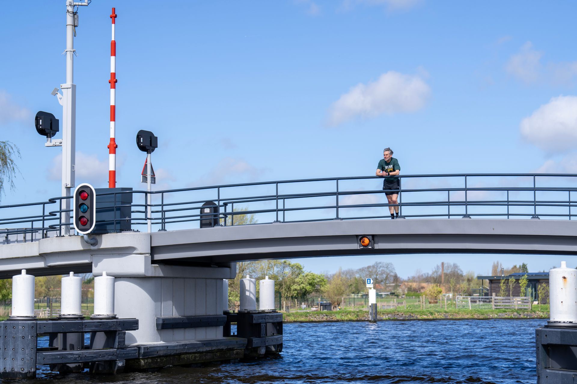 Een man staat op een brug over een watermassa.