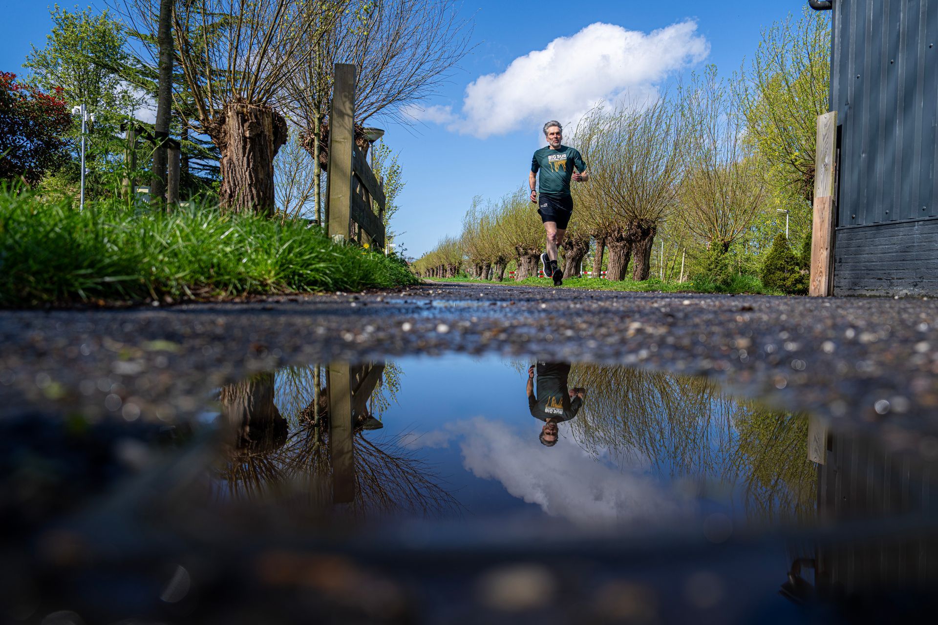 Een man rent op een pad naast een plas water.