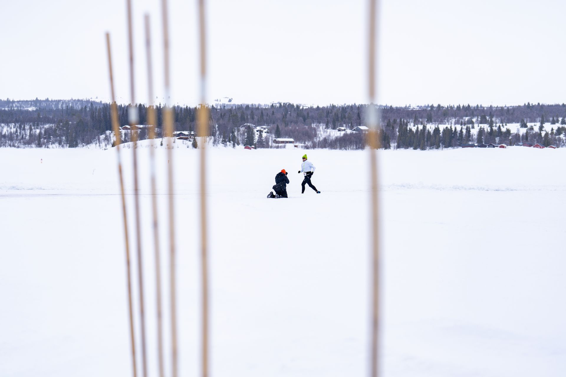 Twee mensen zijn aan het ijsvissen op een bevroren meer.