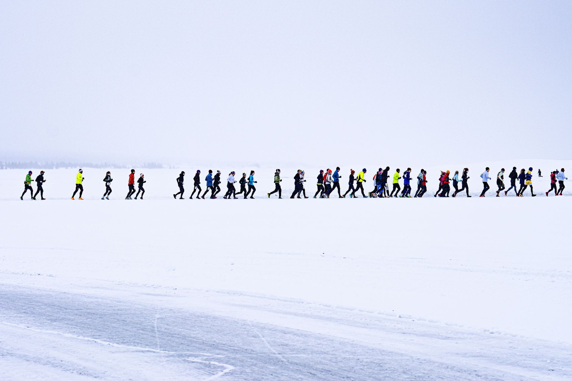 Een groep mensen loopt in een rij door de sneeuw.