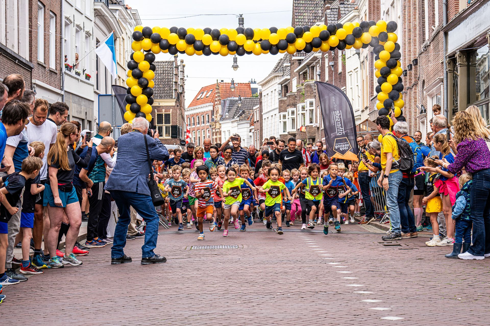 Een groep kinderen rent over een geplaveide straat.