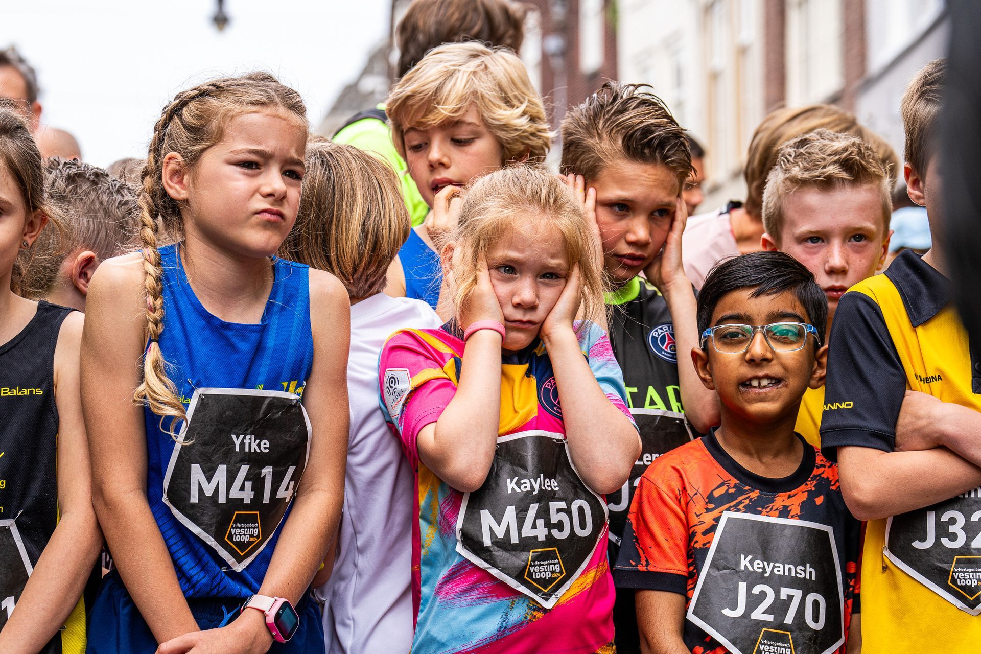 Een groepje kinderen staat naast elkaar en houdt hun oren dicht.