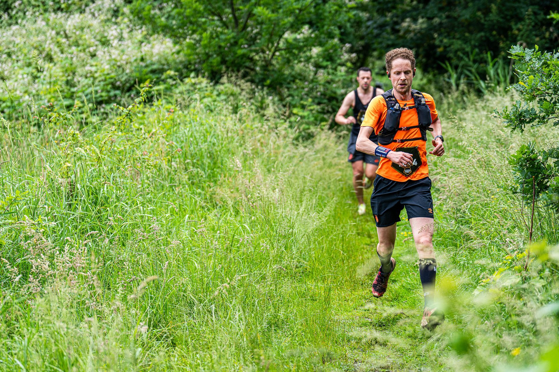 Twee mannen rennen op een pad in het bos.