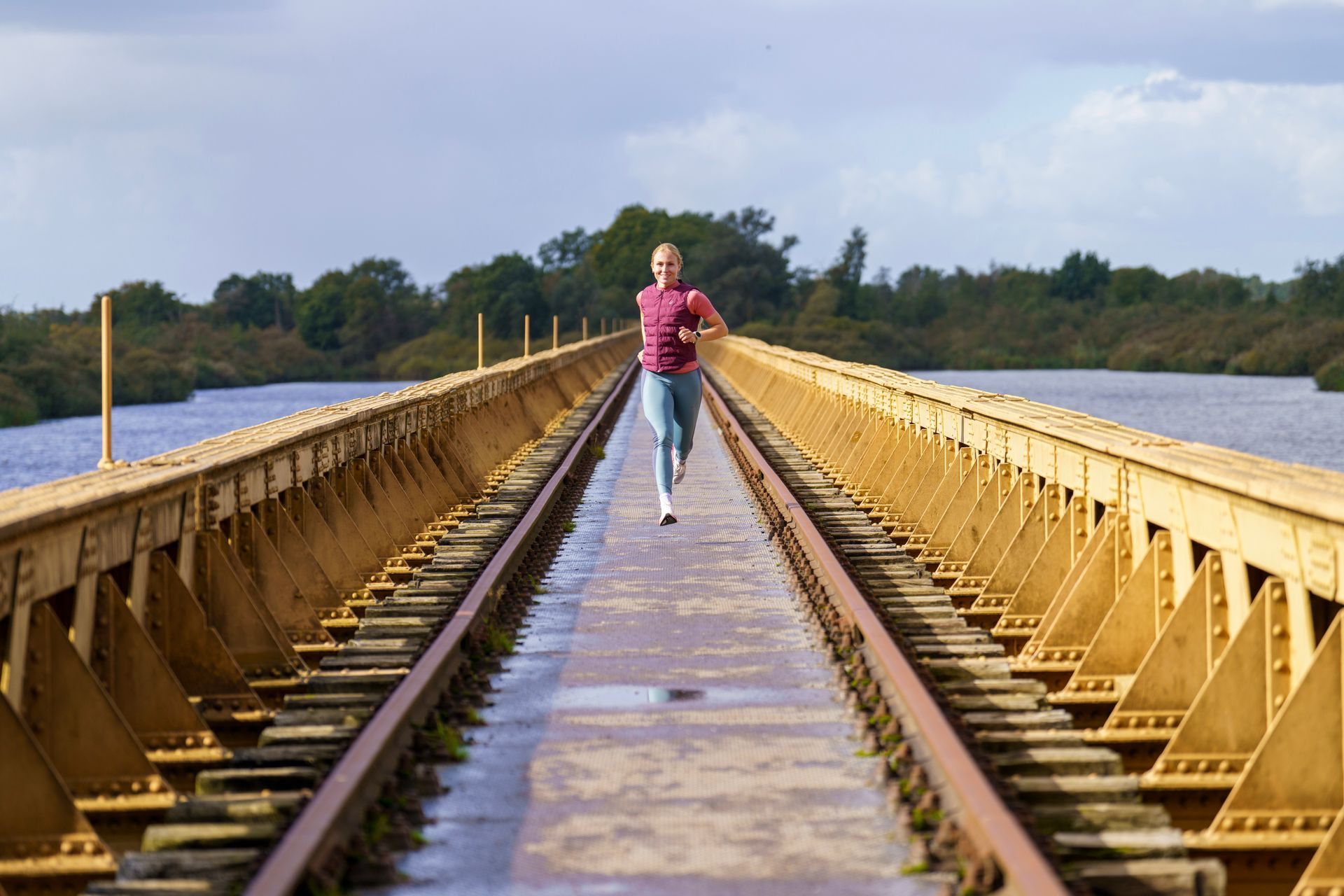 Een vrouw in een roze shirt rent over treinrails