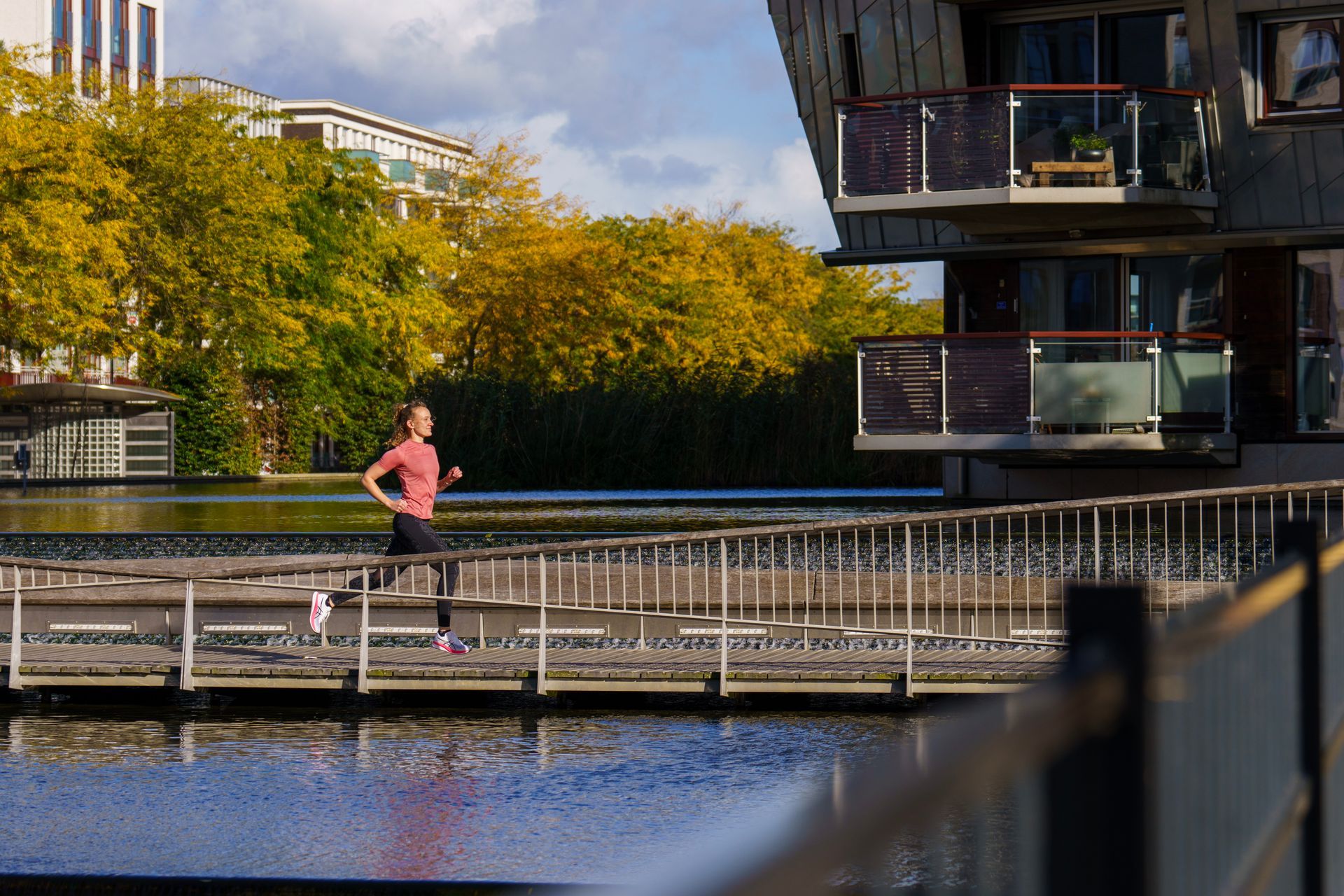 Een vrouw rent op een steiger naast een watermassa.