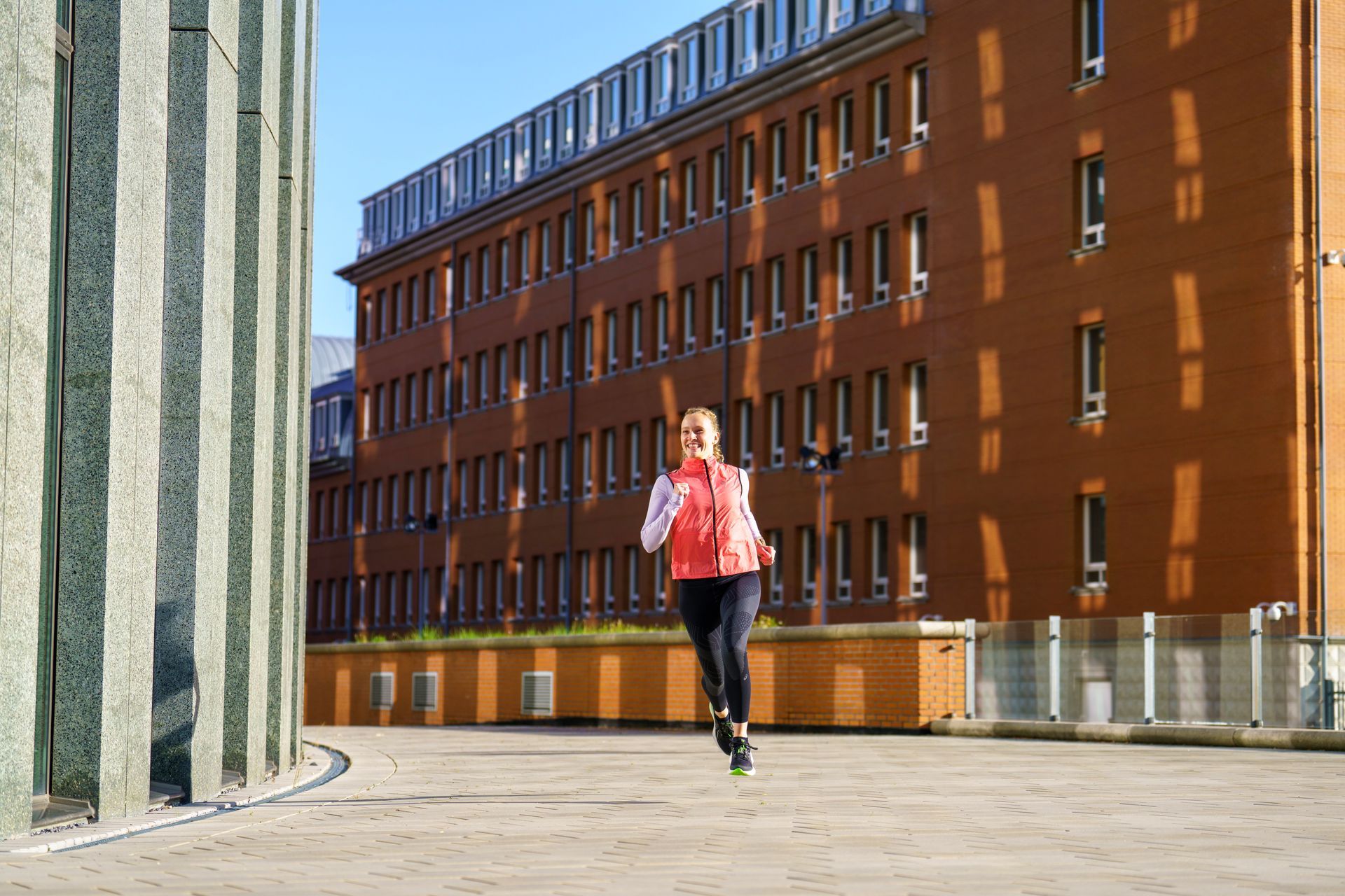 Een vrouw rent voor een groot gebouw.