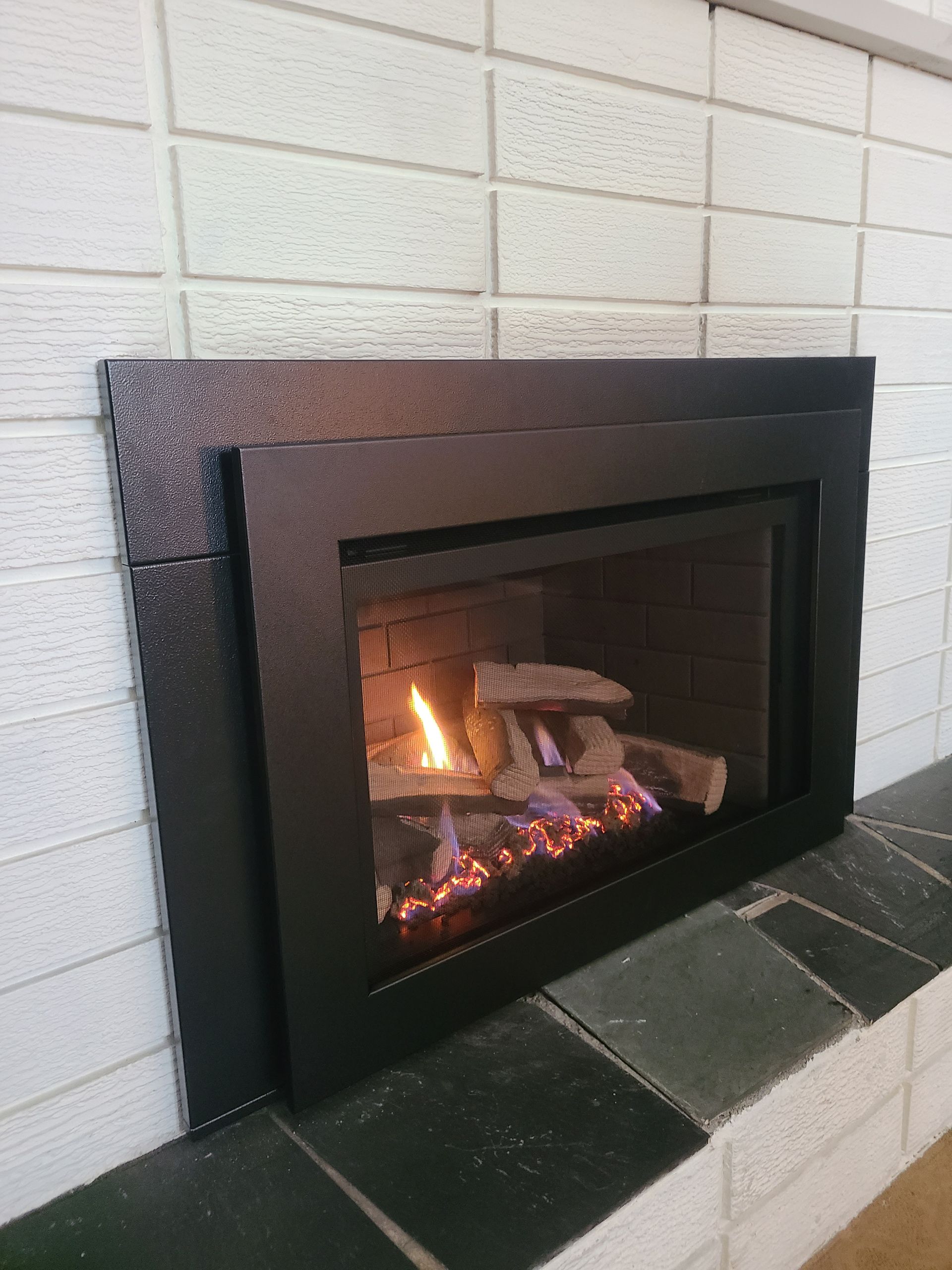 A fireplace with a black frame and a brick wall