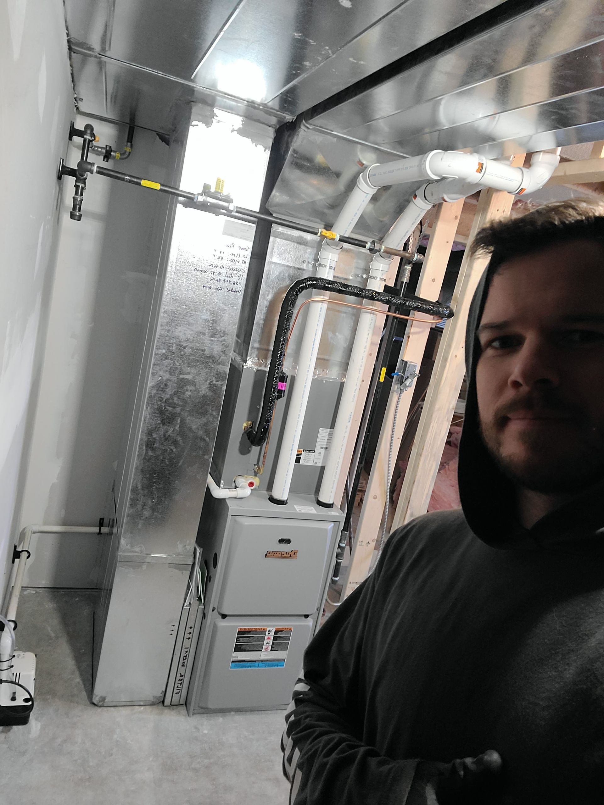 A man is standing in a room with a furnace and pipes.