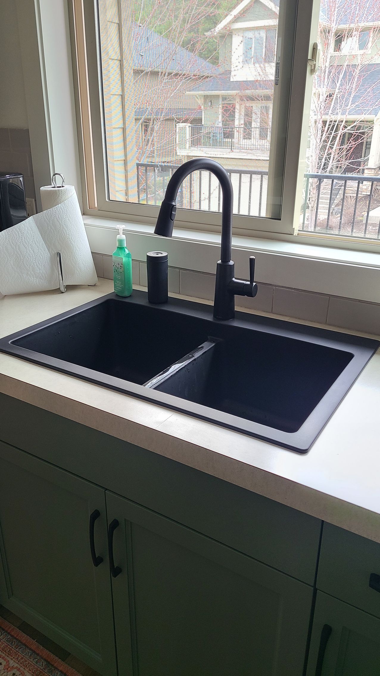 A kitchen sink is sitting on a counter next to a window.
