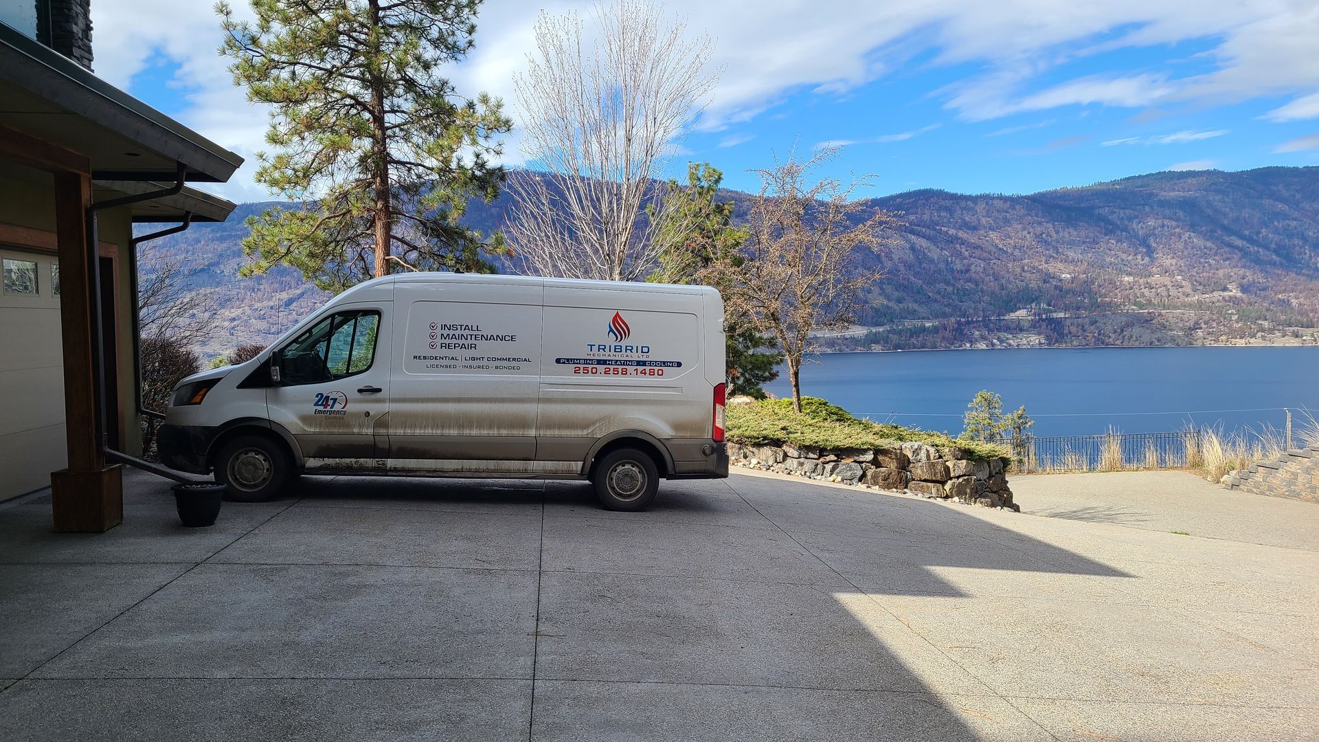 A white van is parked in a driveway next to a house.