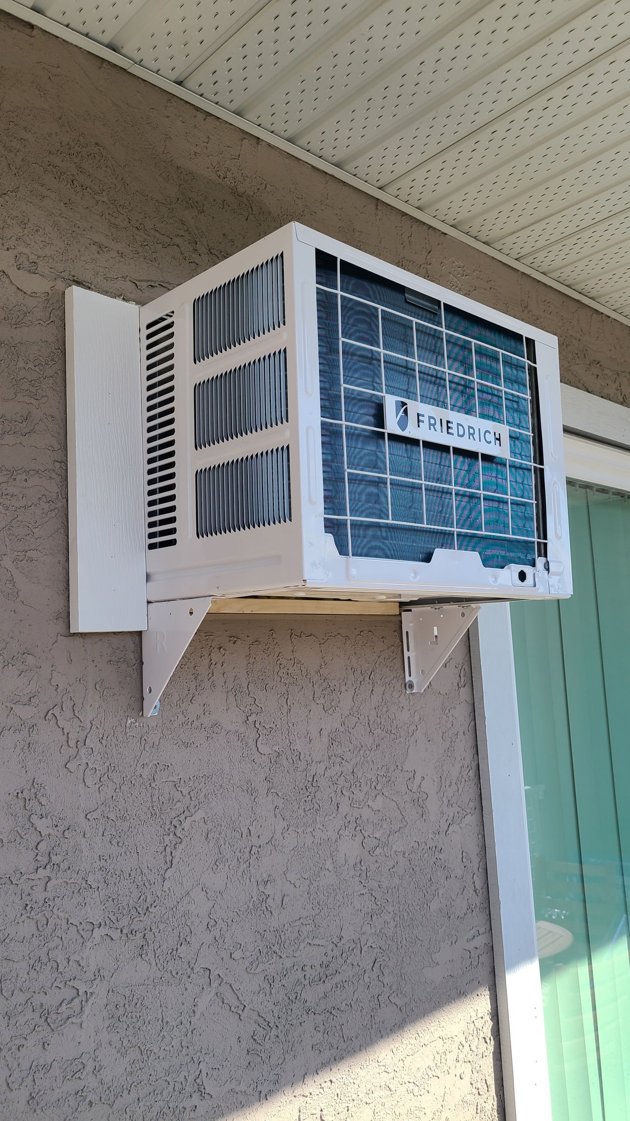 A window air conditioner is mounted on the side of a building.