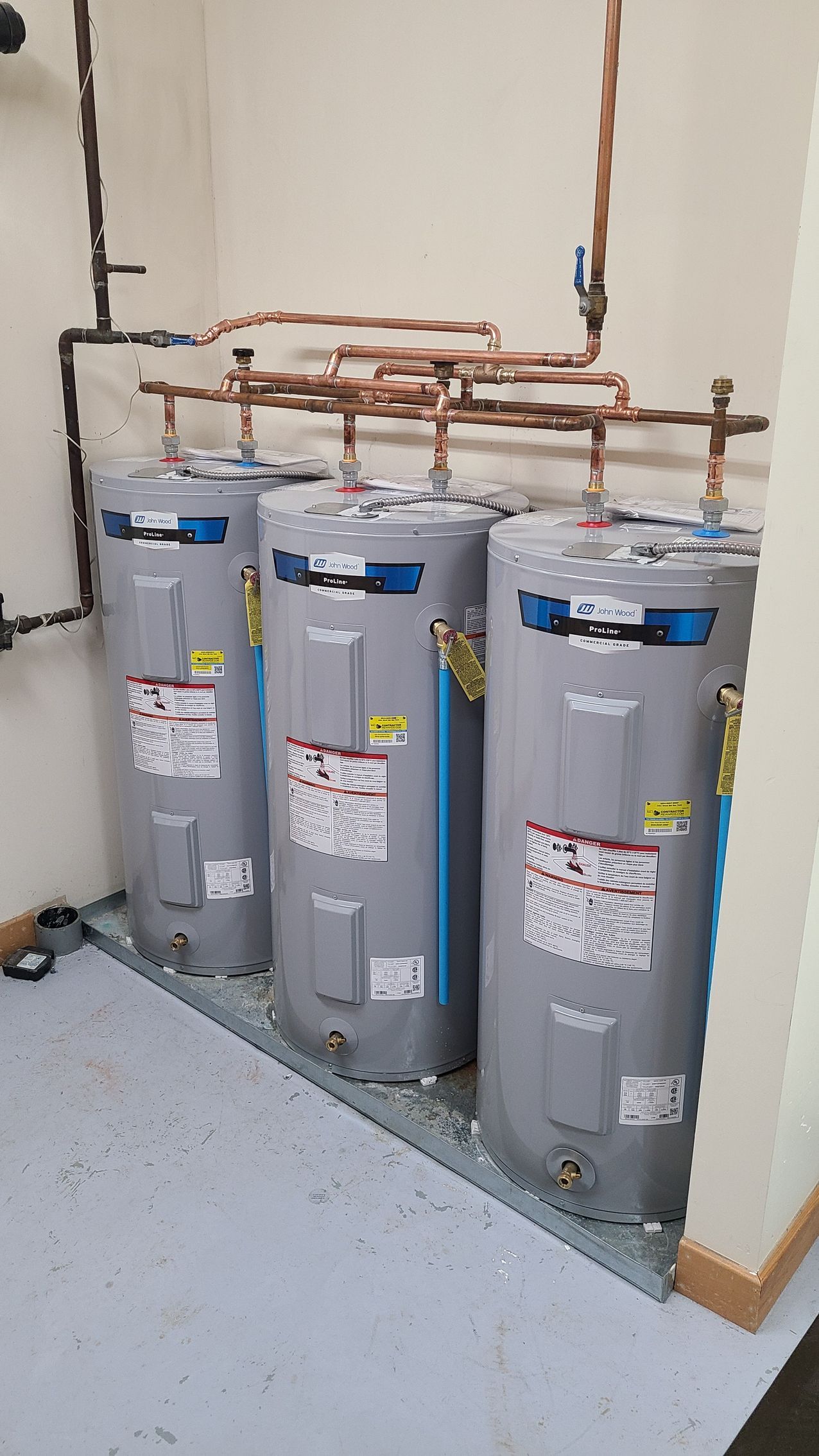 Three water heaters are sitting next to each other in a room.
