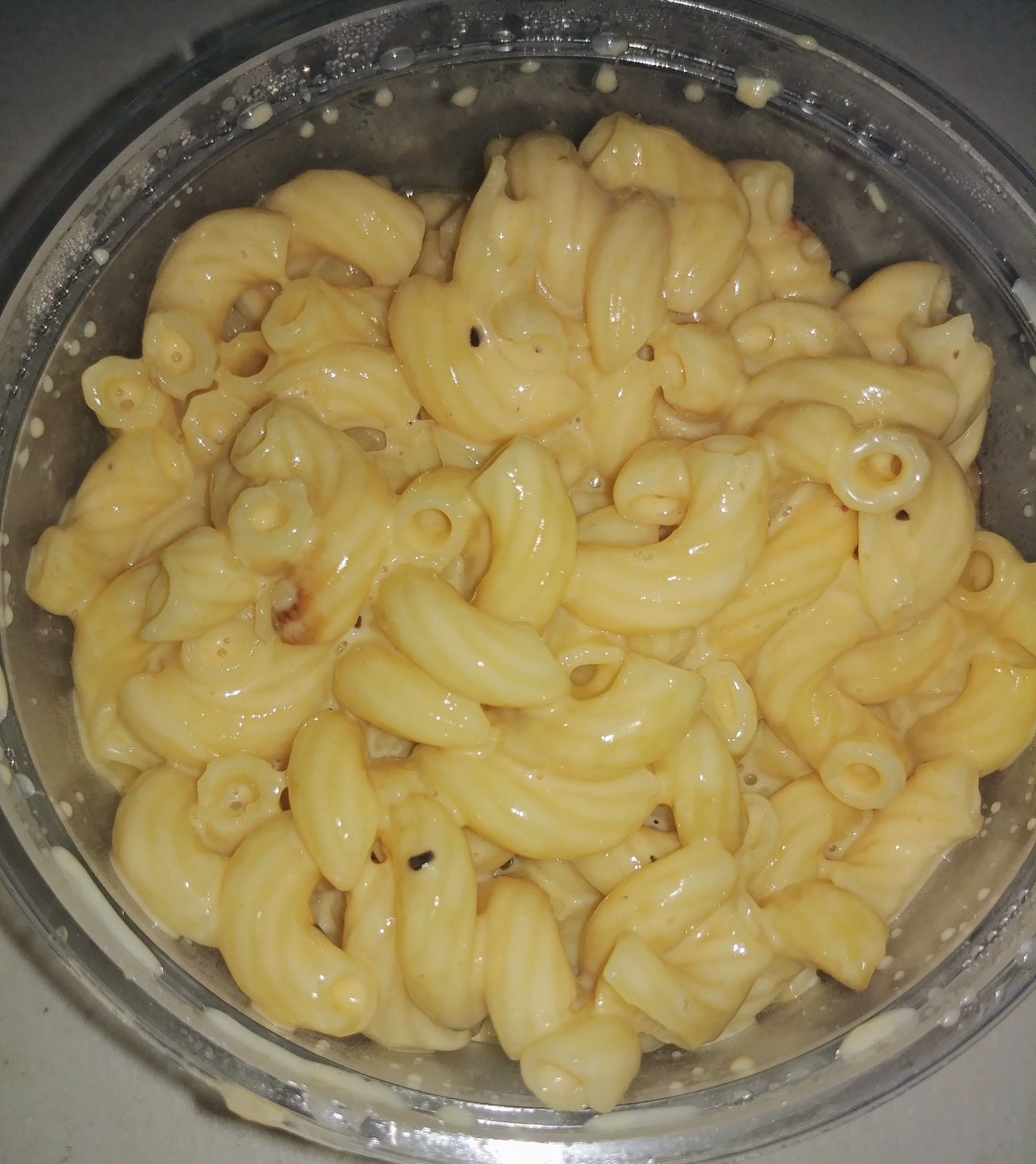 A close up of macaroni and cheese in a plastic container