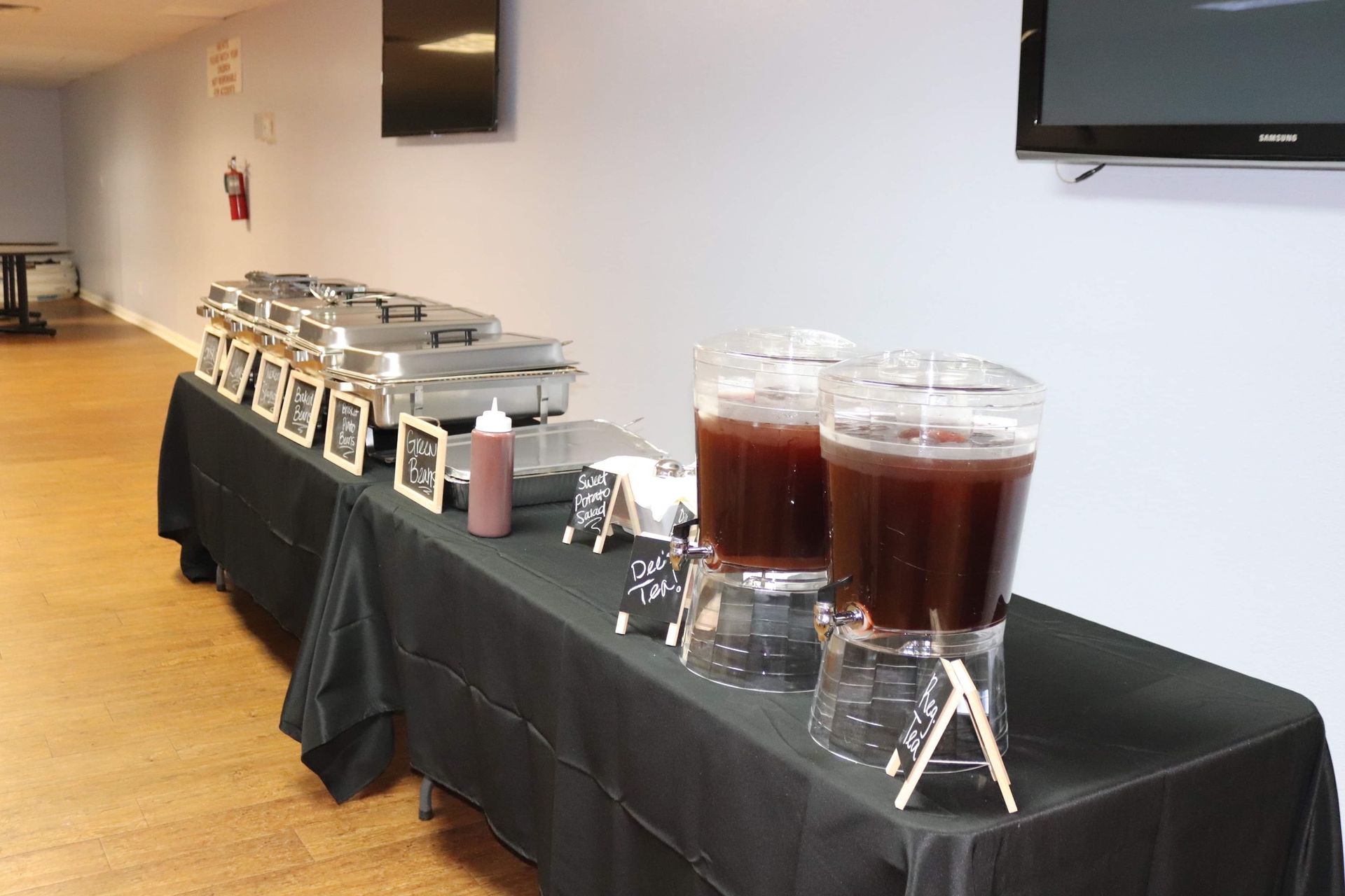 A table with a black table cloth and two drink dispensers on it.