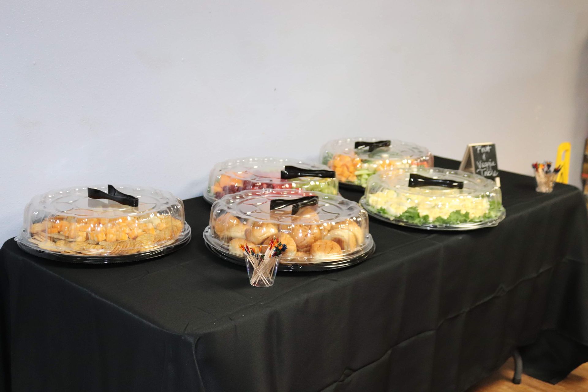 Three trays of food are sitting on a table with a black table cloth.