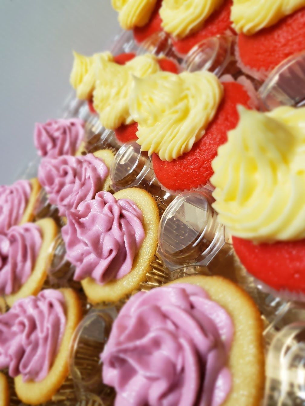 A bunch of cupcakes with purple and yellow frosting