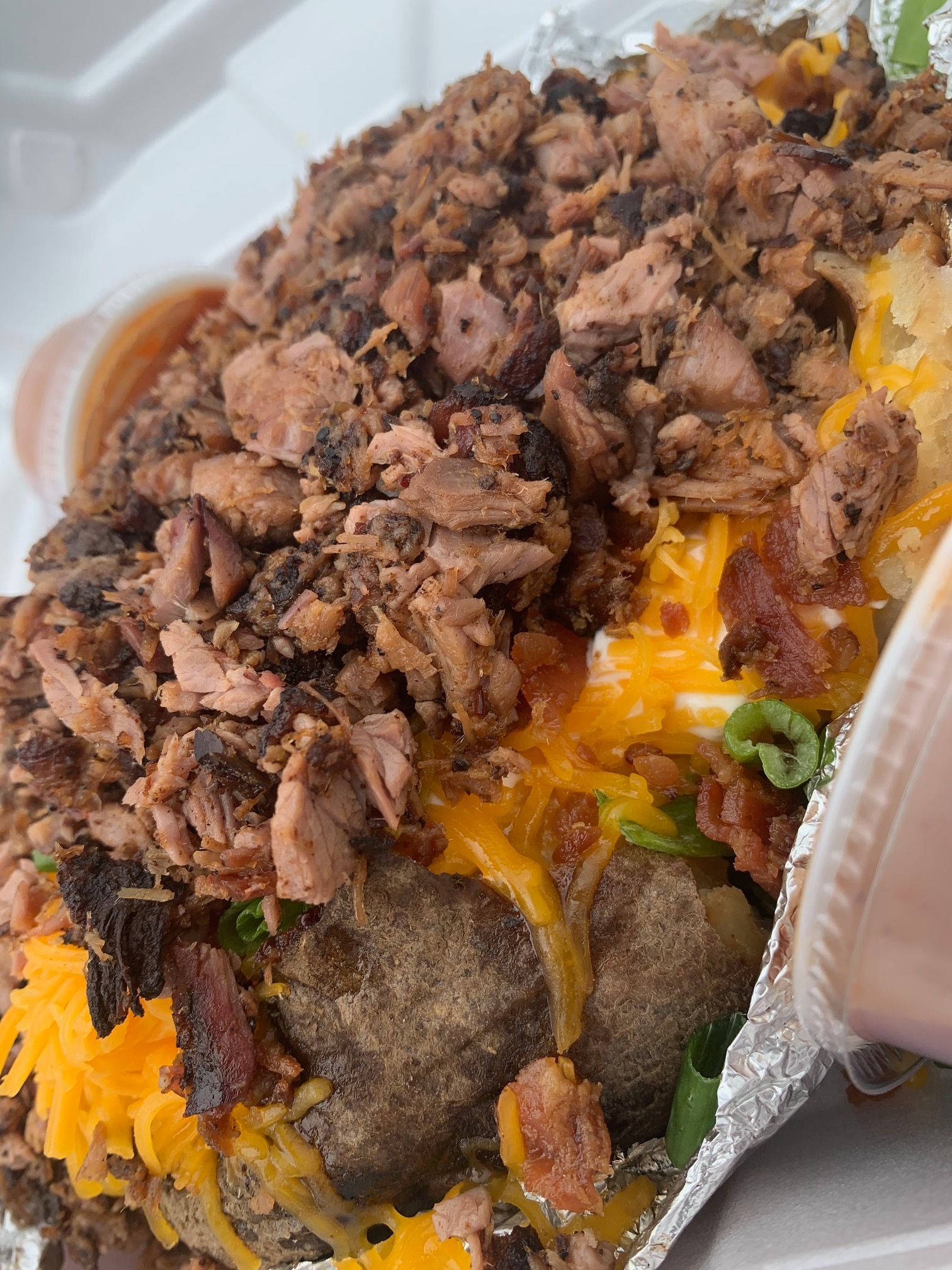 A close up of a plate of food with meat , cheese and bacon.