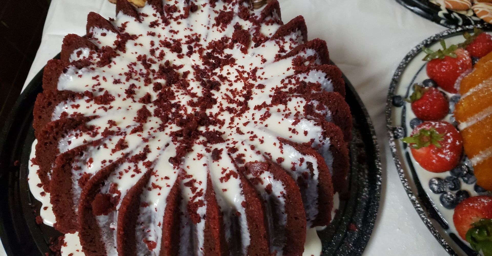 A red velvet bundt cake with white frosting and red sprinkles