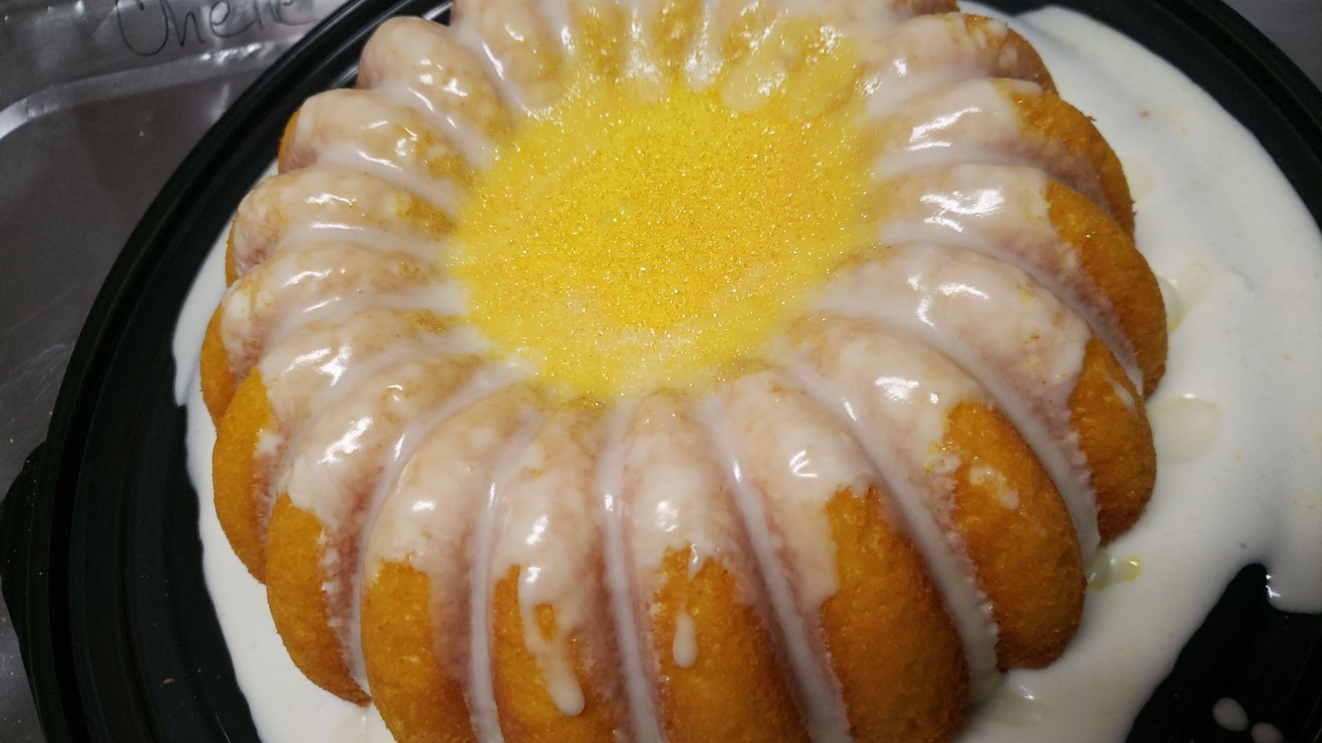 A bundt cake with icing on top is on a black plate.