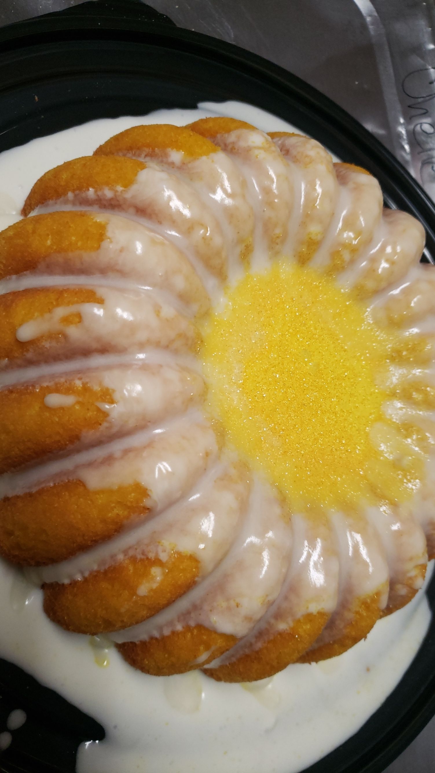 A close up of a bundt cake with icing on a plate.