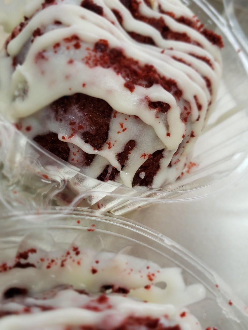 A close up of a red velvet donut with white frosting