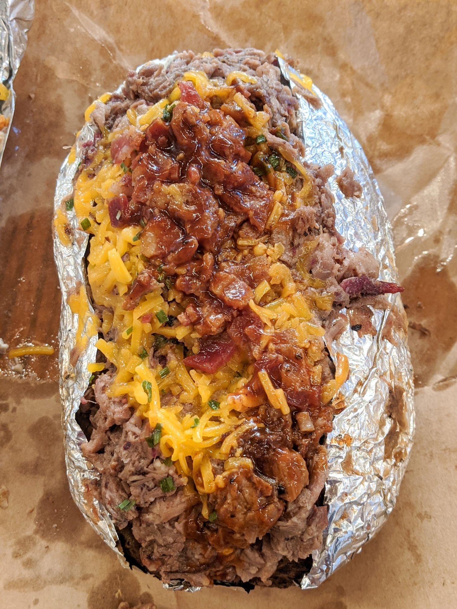 A baked potato covered in meat , cheese and bacon.