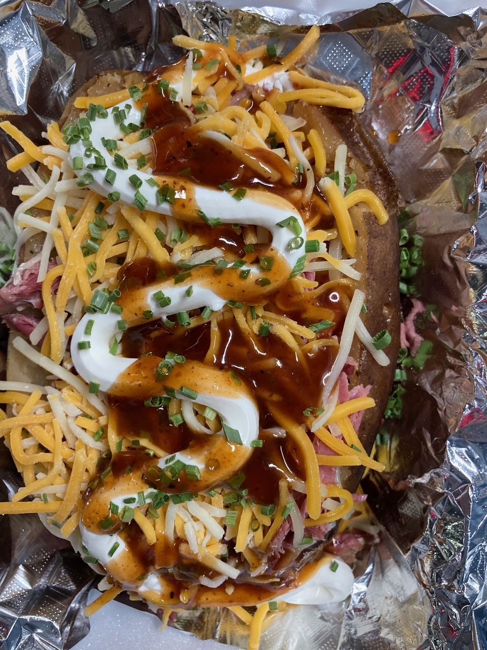 A baked potato with cheese and sauce on it