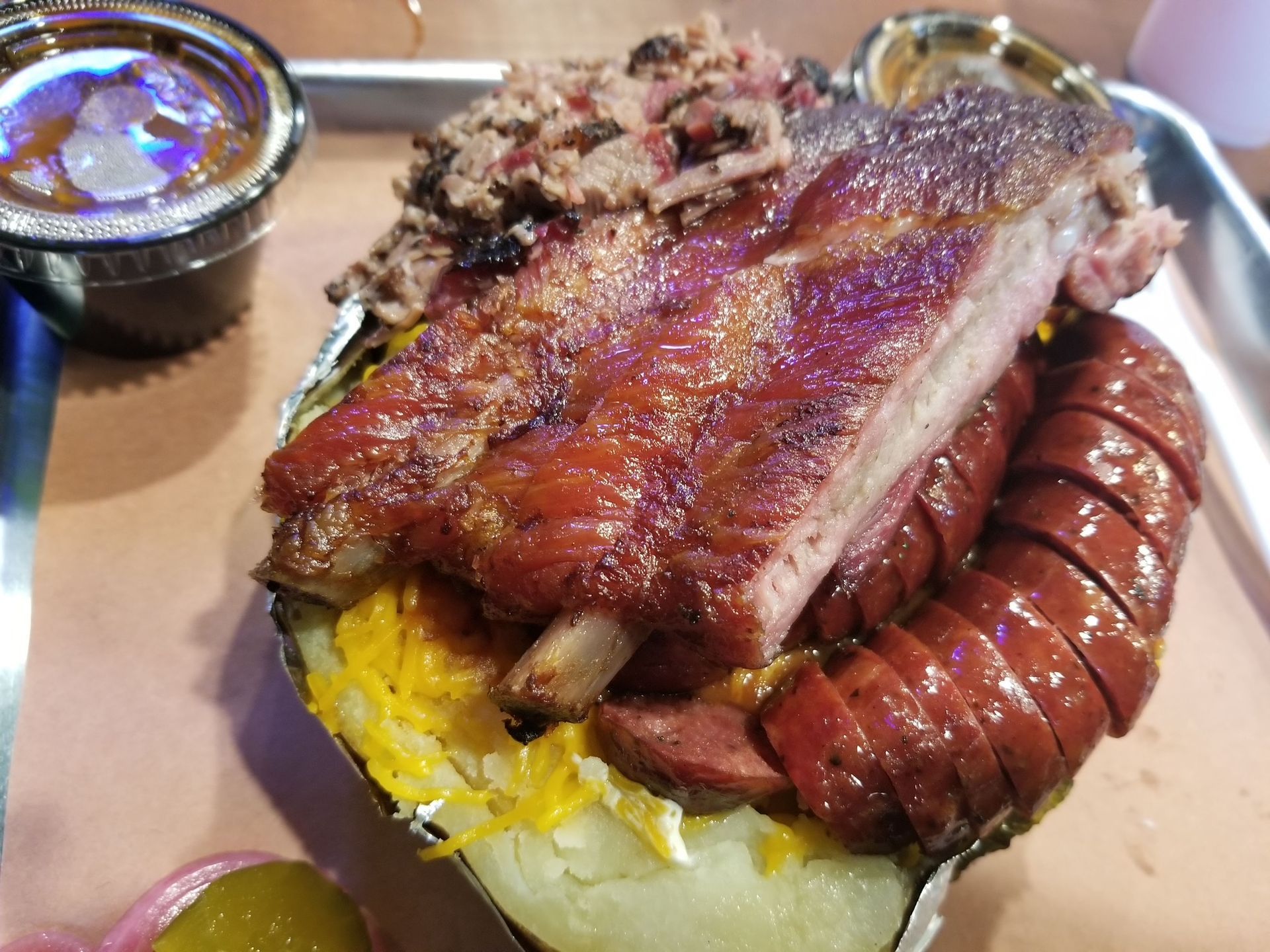 A close up of a plate of food with ribs and sausage on a table.