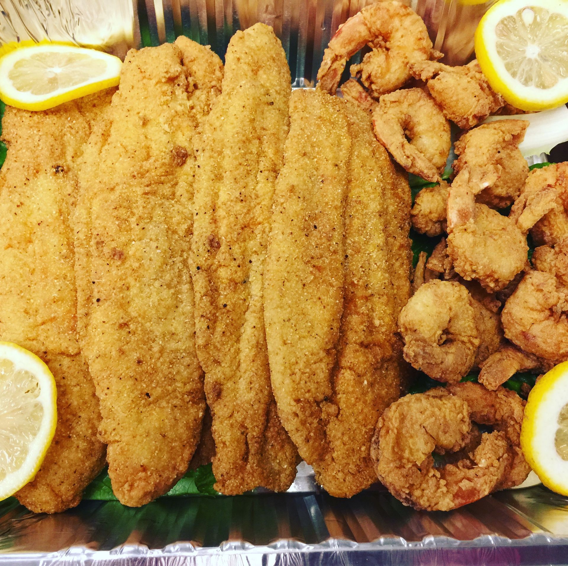 A tray of fried fish and shrimp with lemon slices