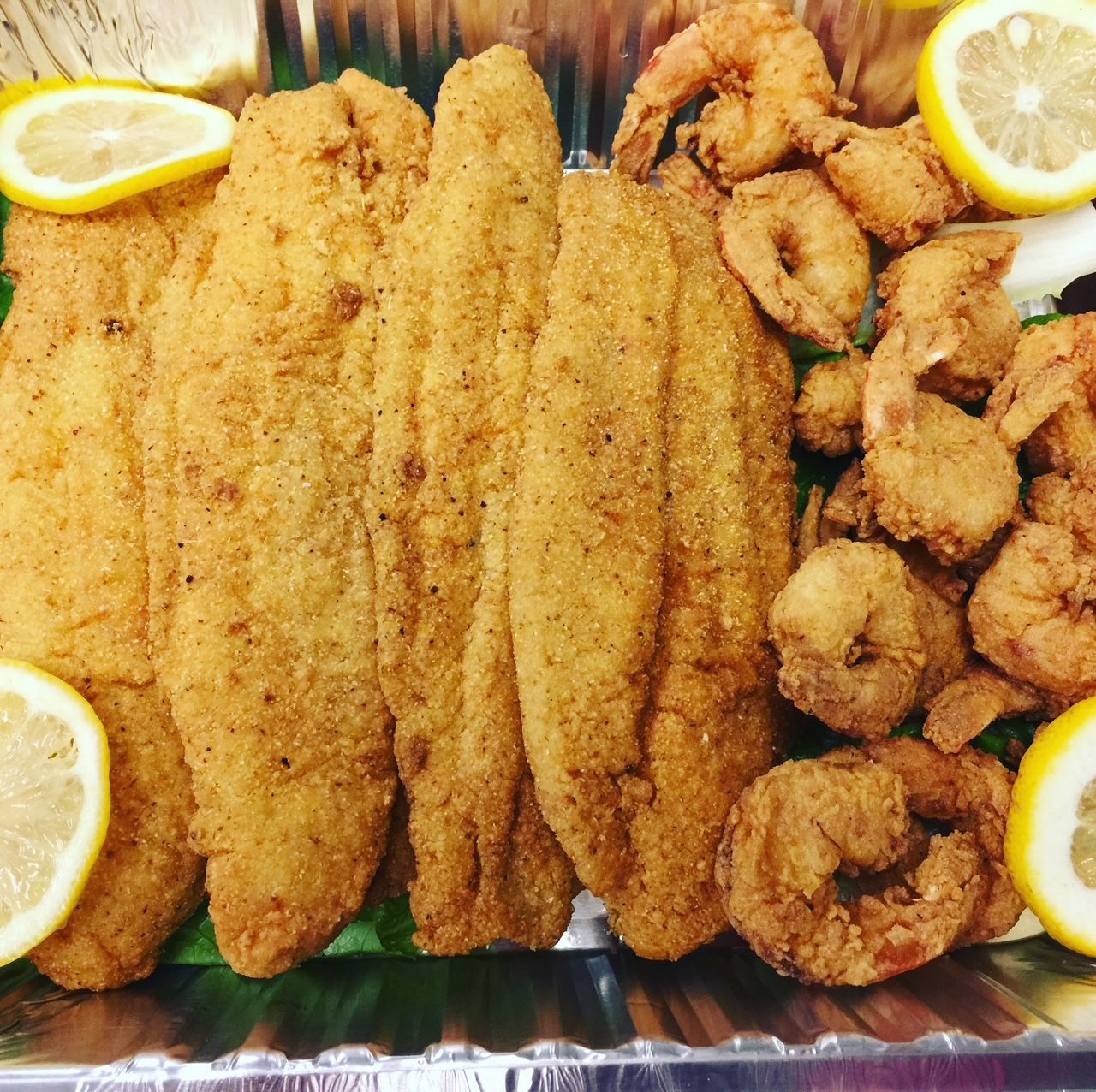 A tray of fried fish and shrimp with lemon slices