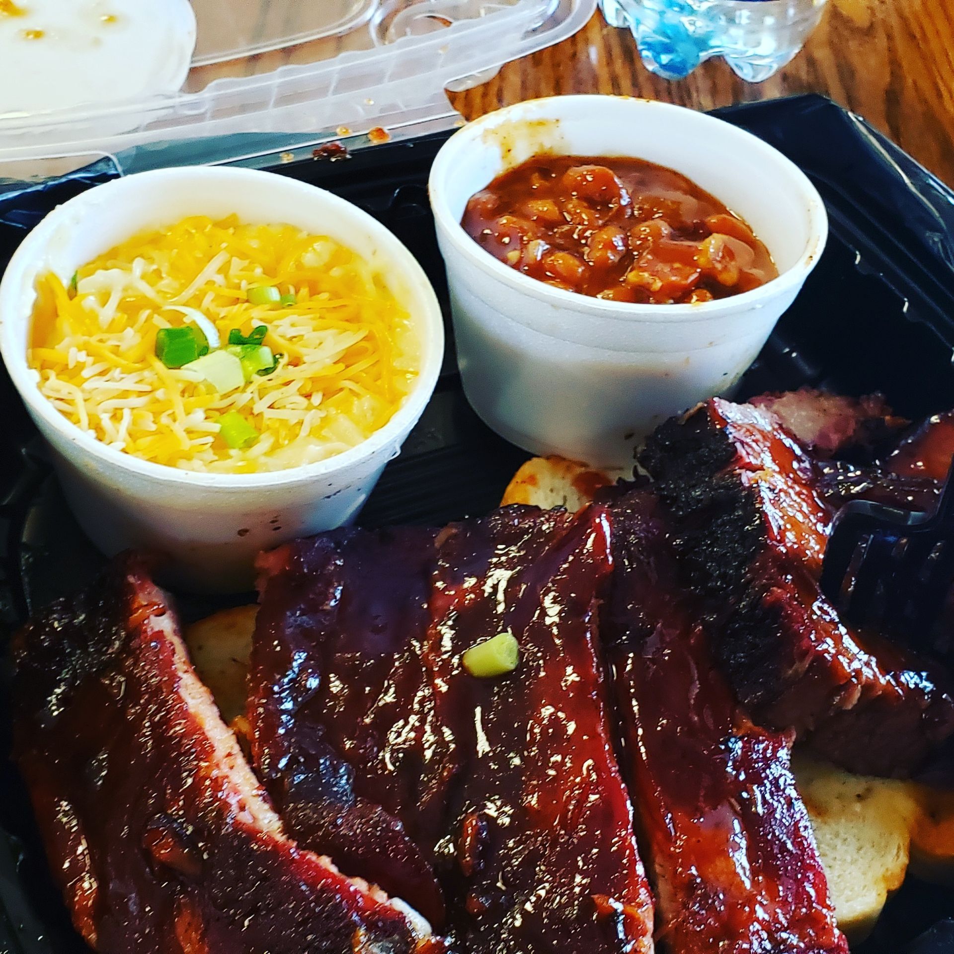 A tray of food with ribs beans and corn on the cob