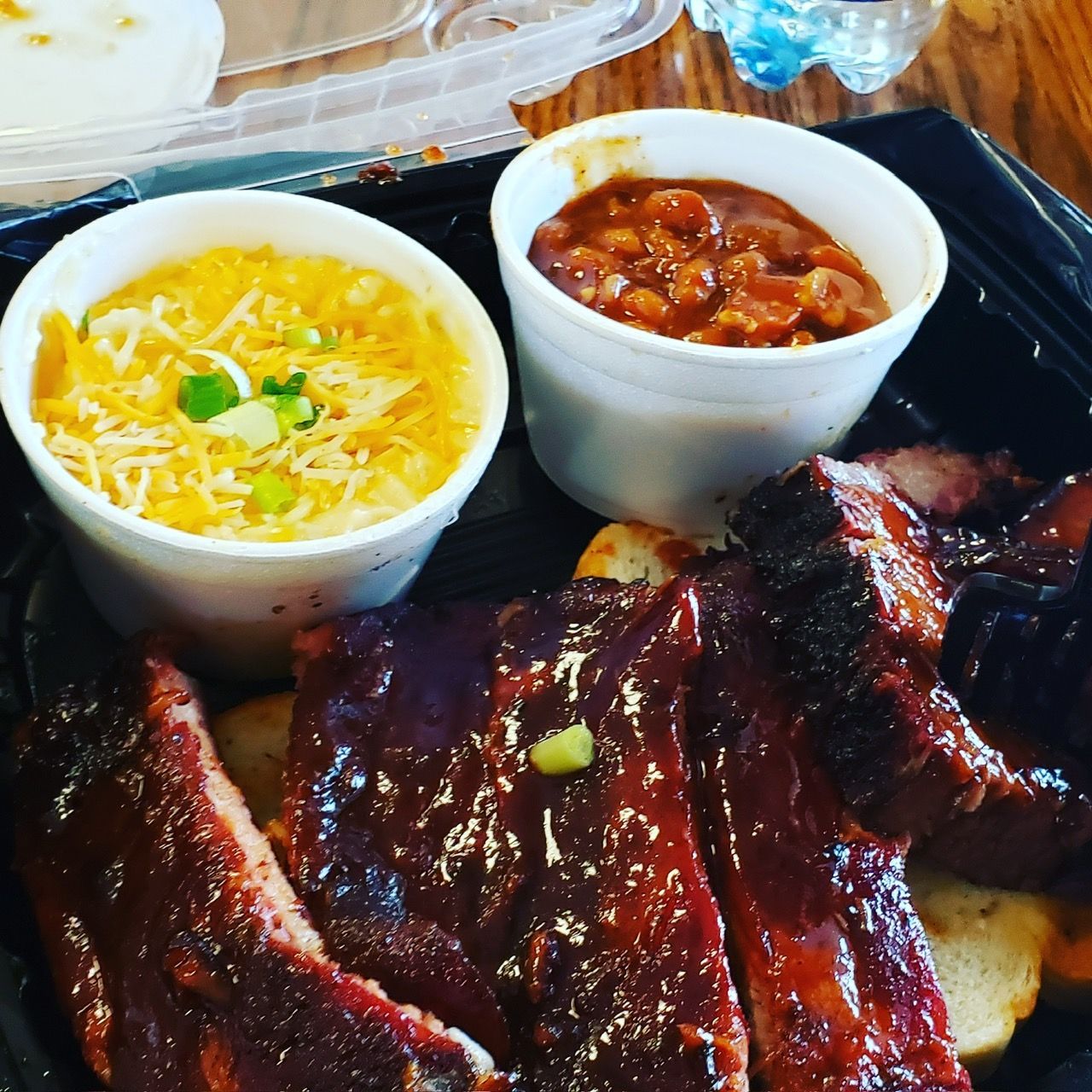 A tray of ribs and two bowls of sauce on a table