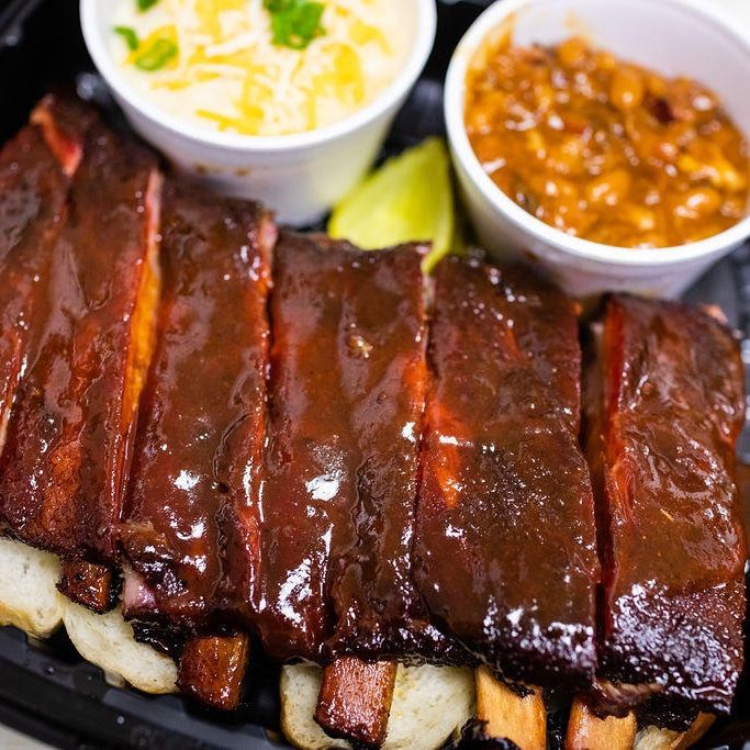 A close up of a plate of food with ribs and beans
