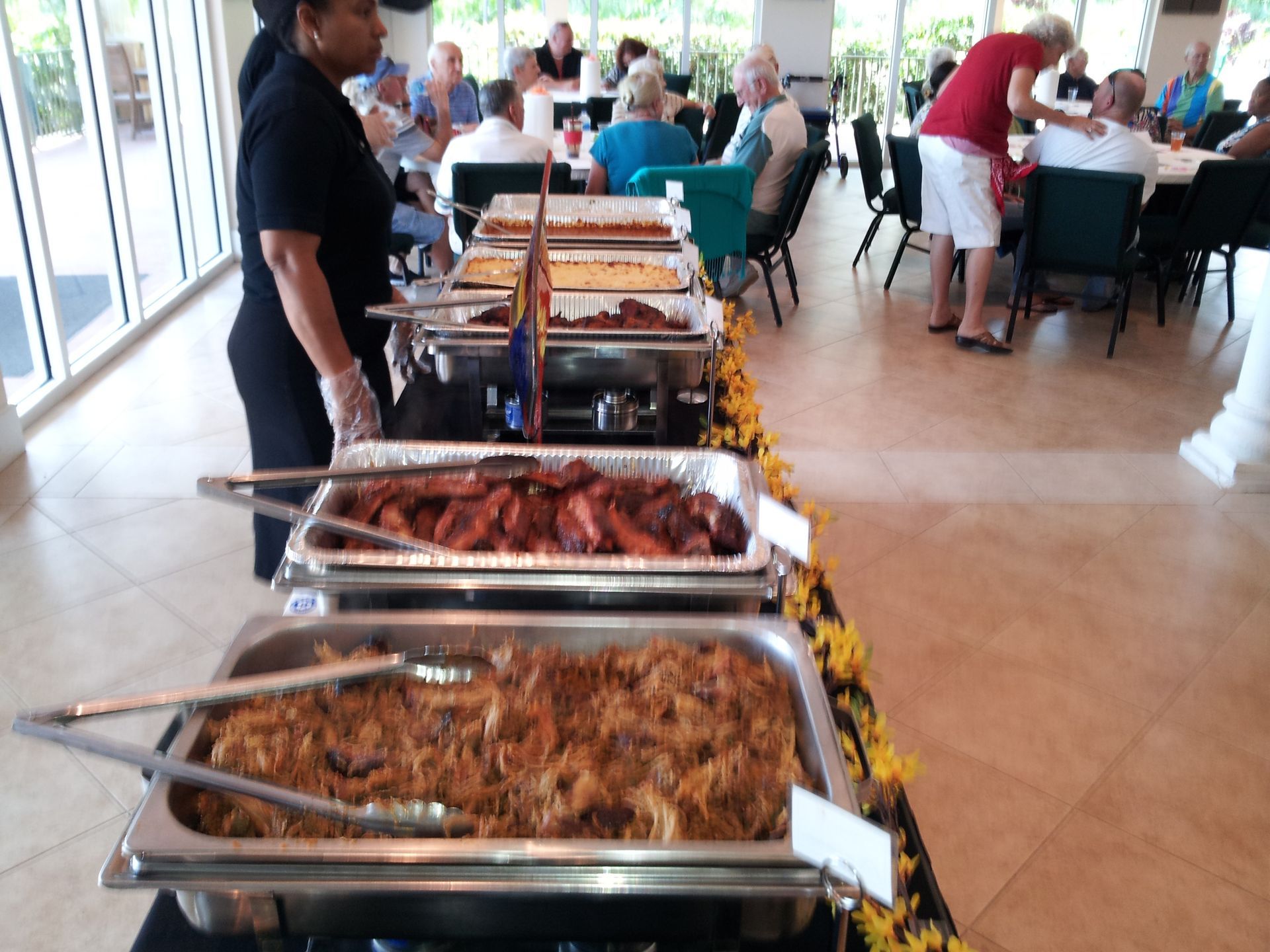 A buffet line with people sitting at tables in the background