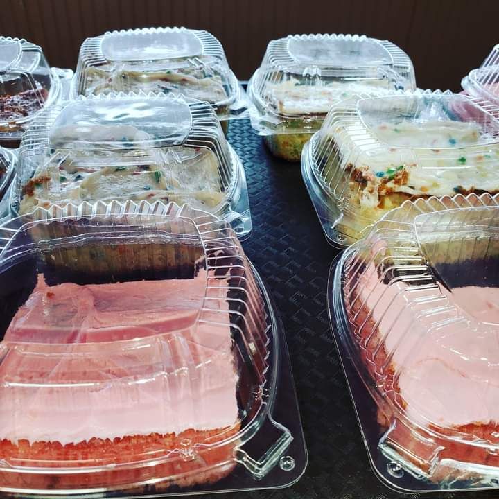 Several pieces of cake are in plastic containers on a table