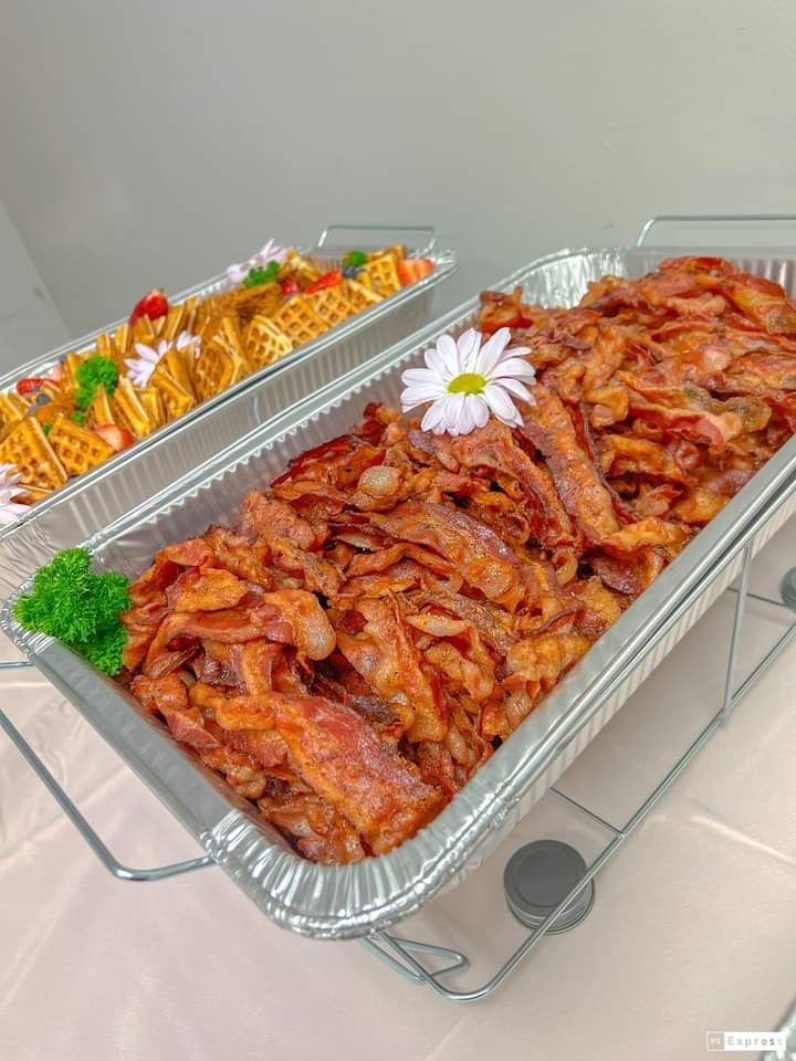 A tray of bacon is sitting on top of a table next to a tray of french fries.