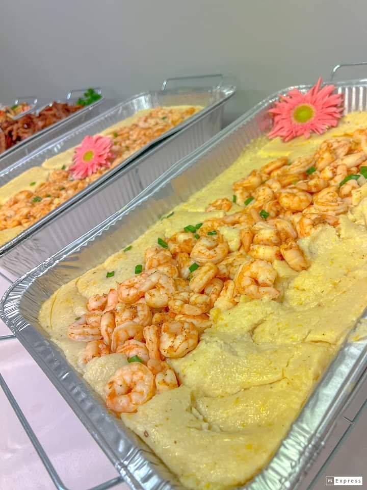 A tray of food with shrimp and polenta on a table.
