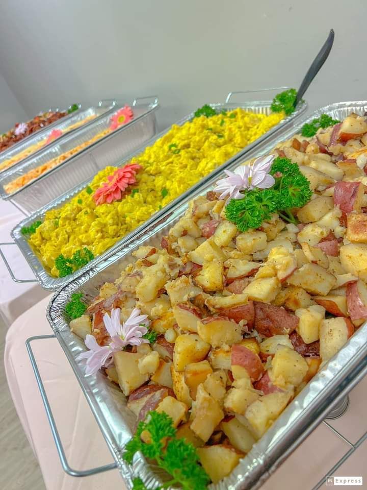 Several trays of food on a table including rice and potatoes