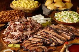Barbecue feast: brisket, pulled pork, sides of beans, slaw, potatoes, rolls, pickles, and onions.