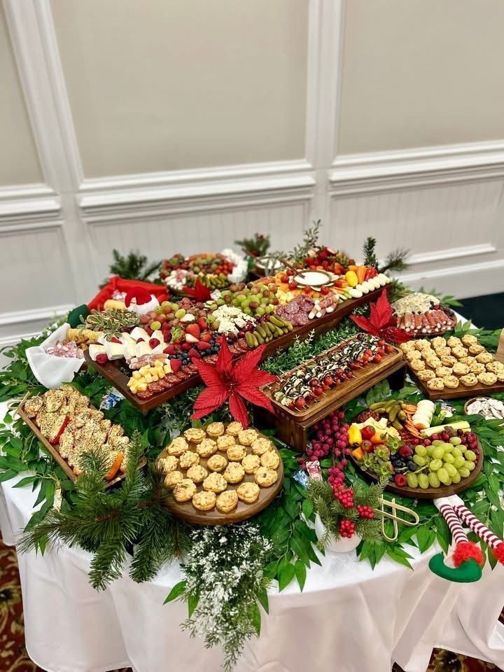 Charcuterie board with skewers of cherry tomatoes, mozzarella, and balsamic glaze. Other snacks include pickles, fruit, and crackers.