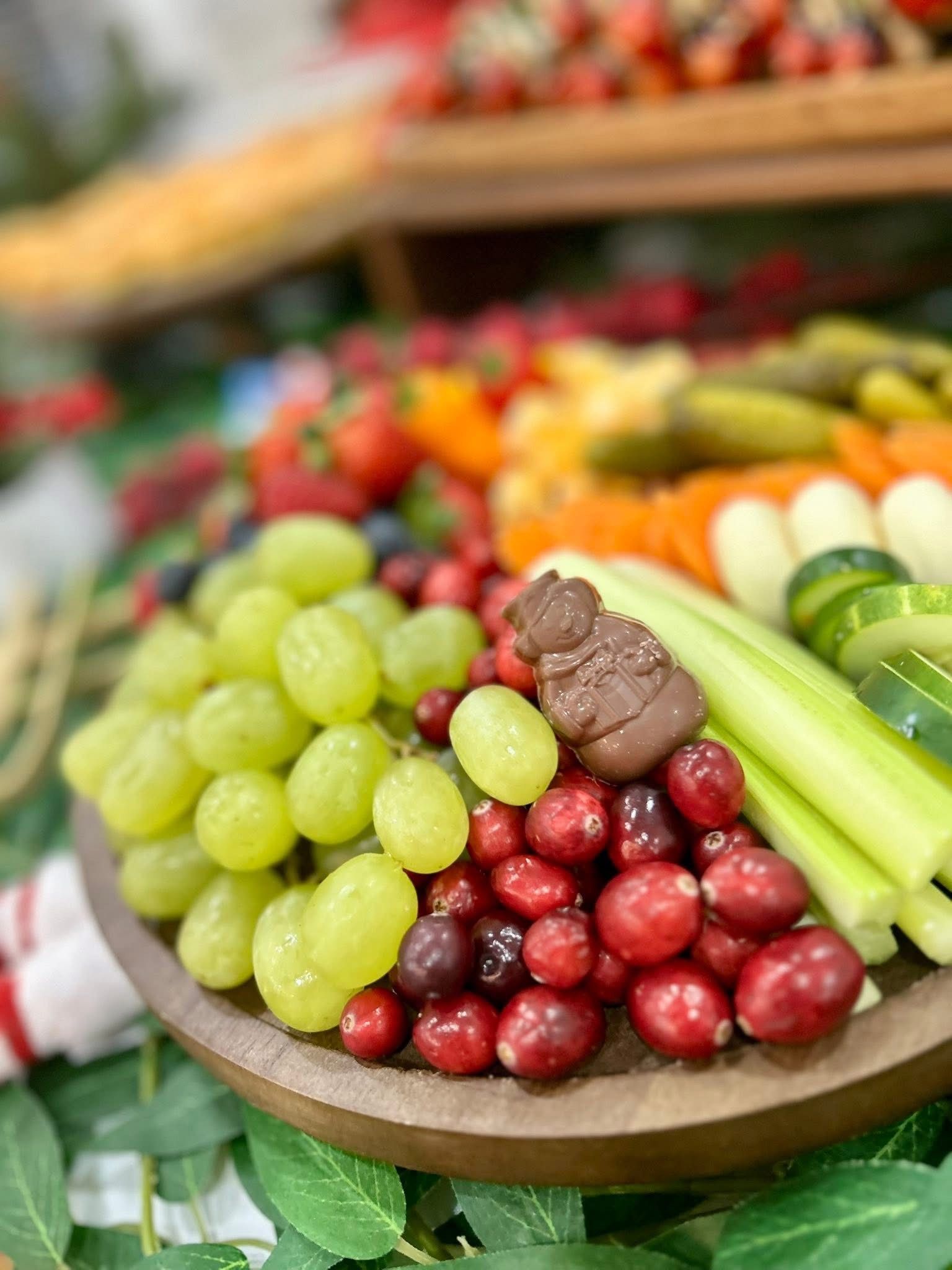 Charcuterie board with various food items arranged for a festive holiday gathering, including fruits, vegetables, cheeses, and meats.